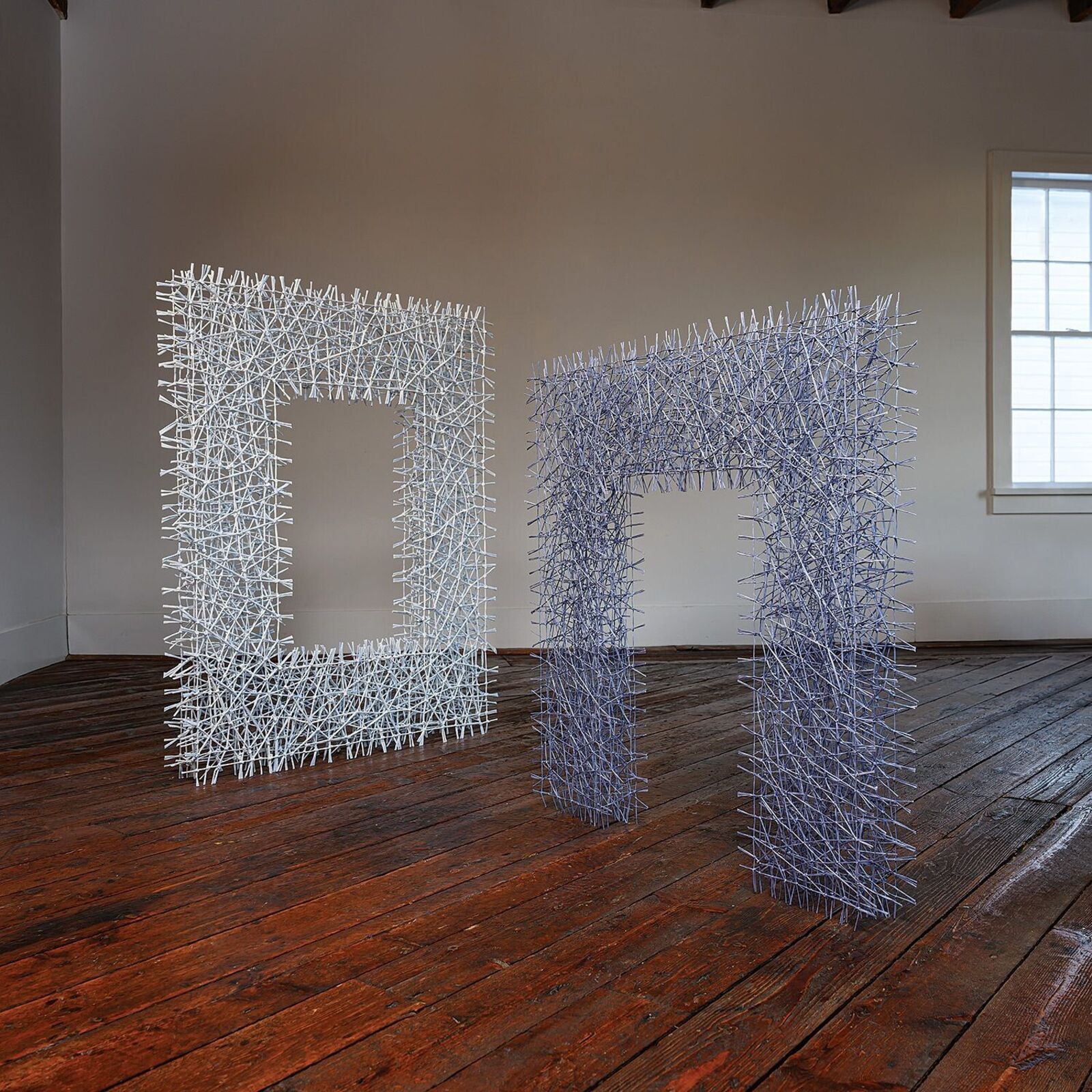 A white, frame-shaped sculpture made of tangled sticks or twigs.