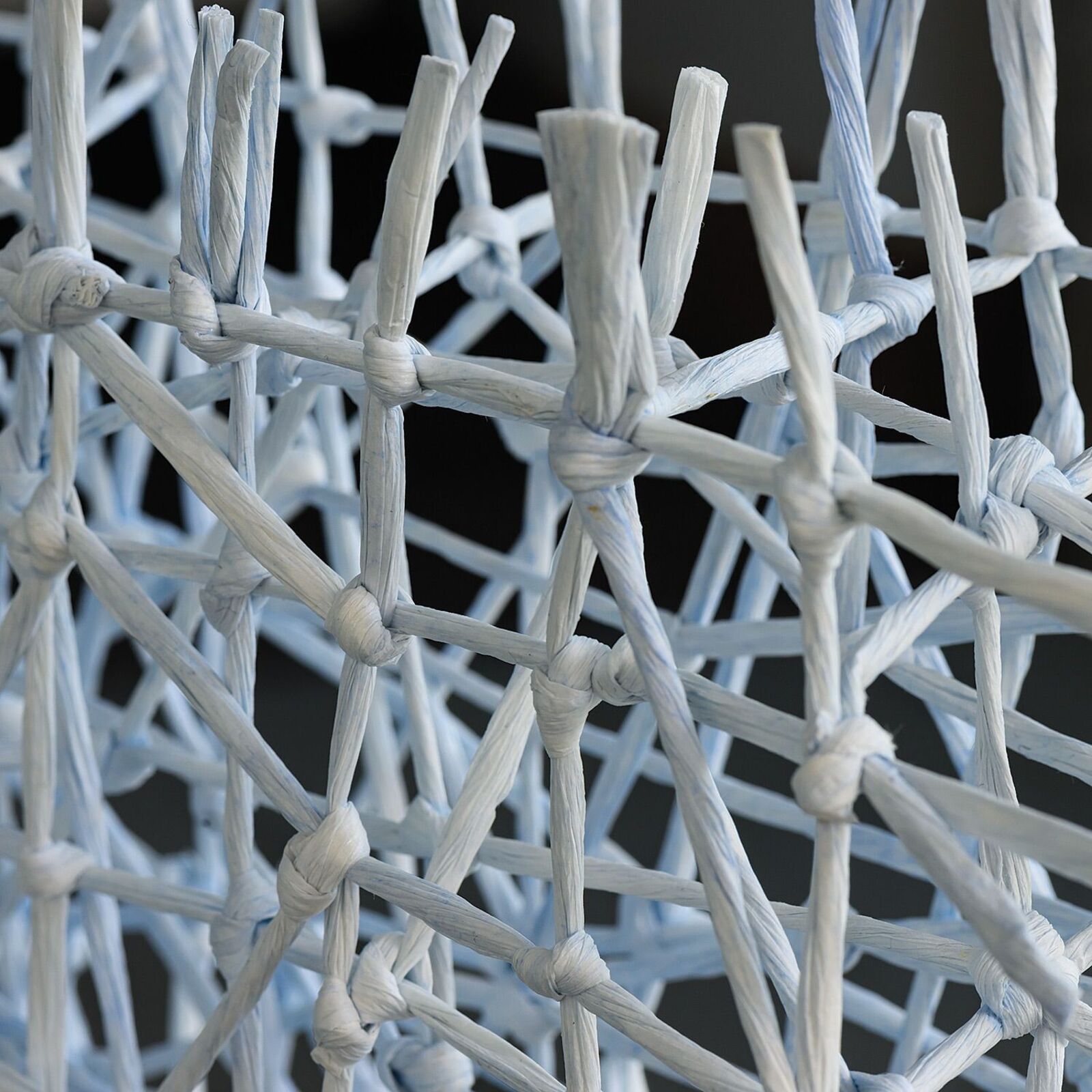 A white, frame-shaped sculpture made of tangled sticks or twigs.