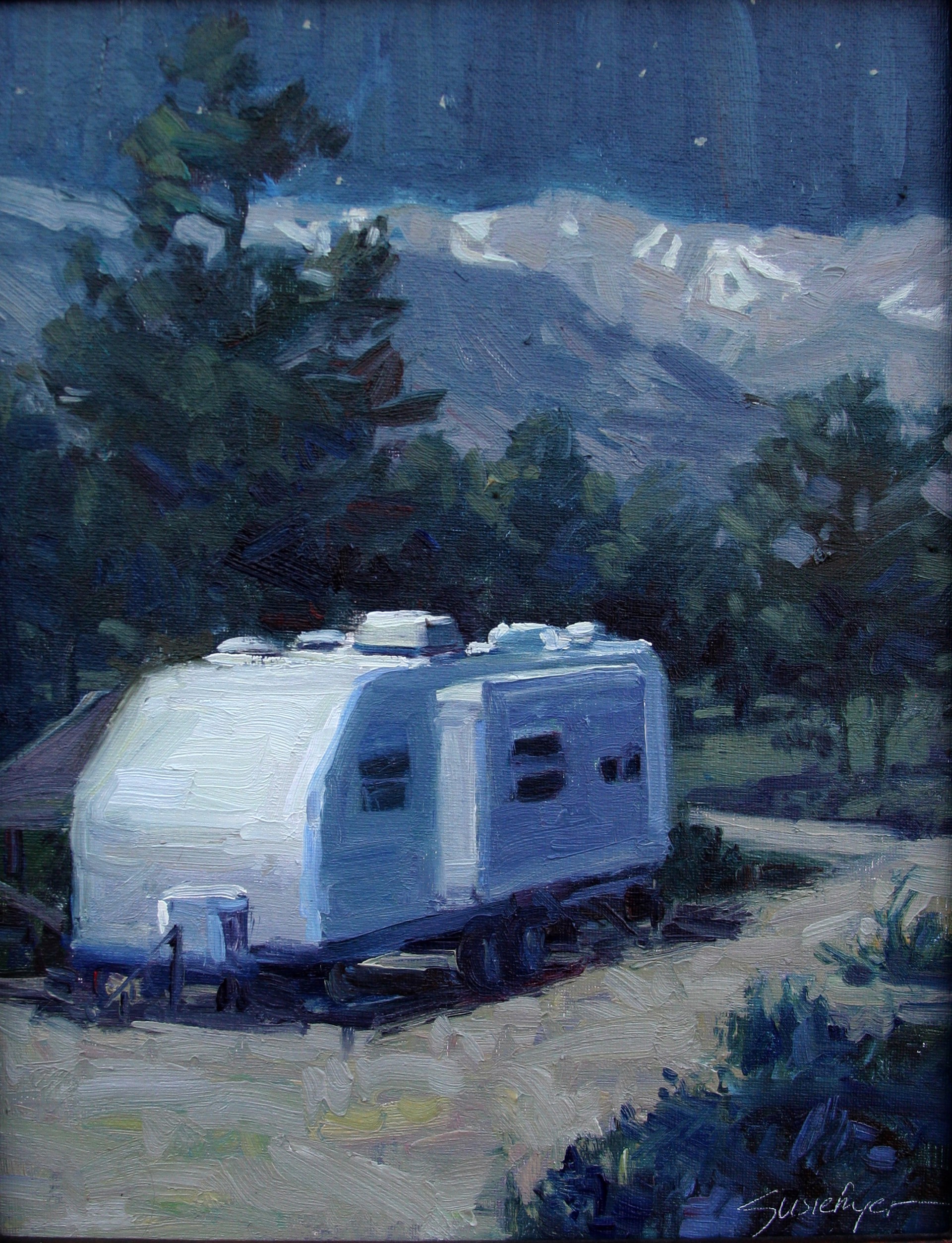 A white caravan rests on a dirt road in front of dark mountains under a starry night sky.