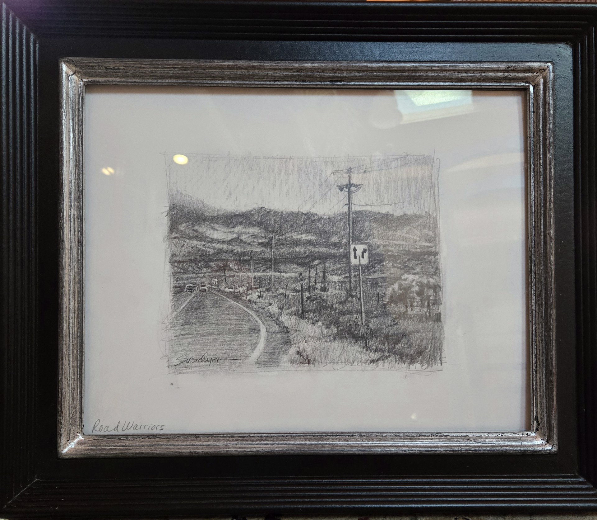 A monochromatic road scene with hills and a utility pole.