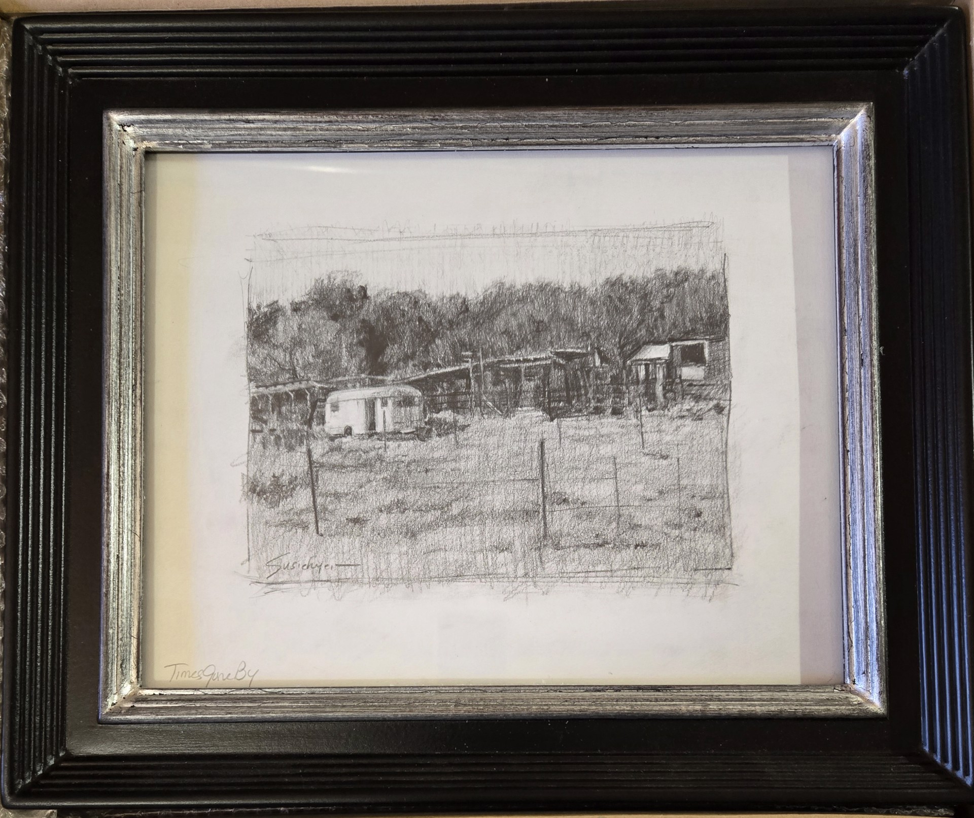 A monochromatic pencil sketch of a rustic rural scene featuring an old trailer and weathered structures.