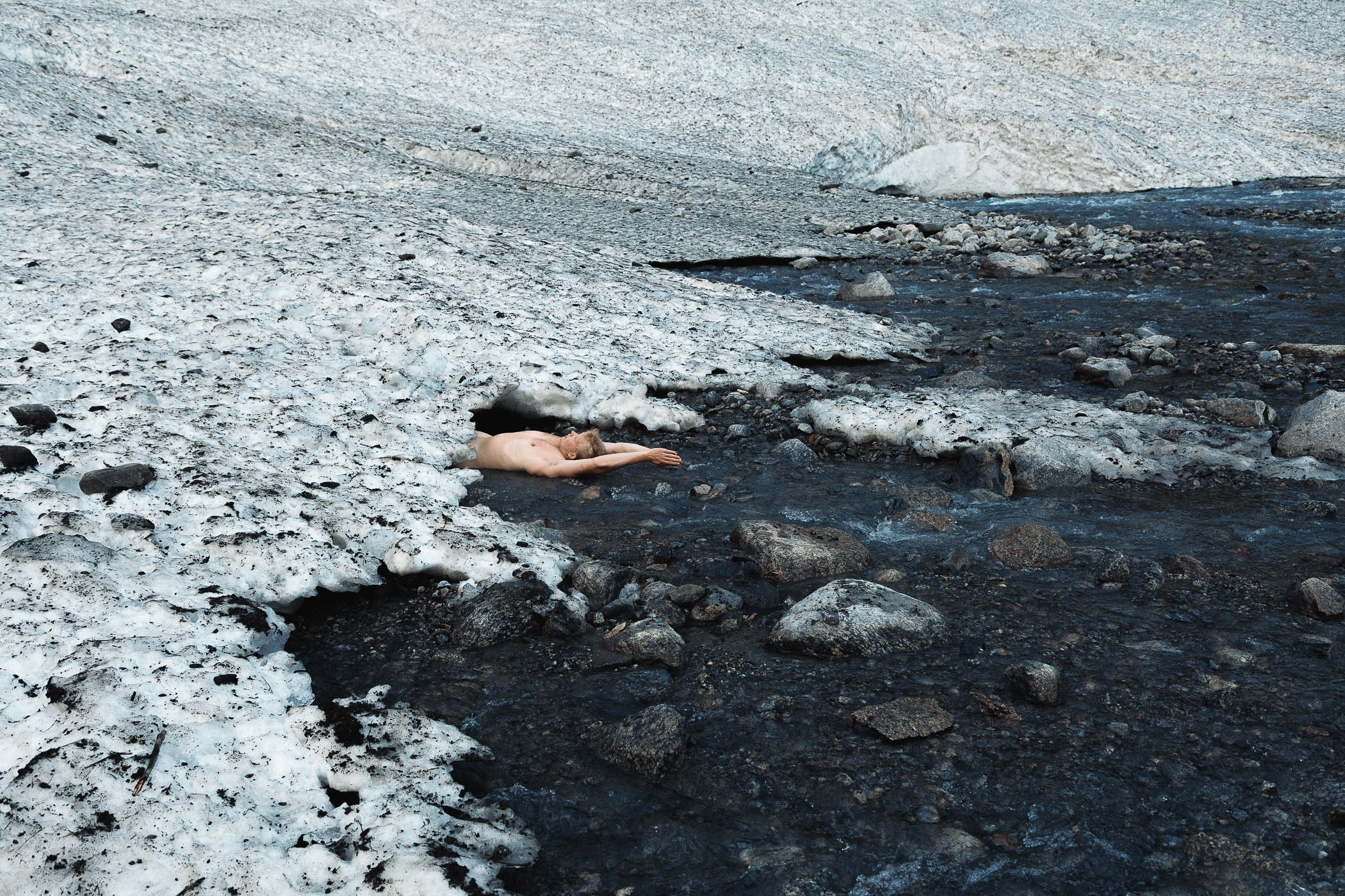 A man laying on the ground in the middle of a snow covered field.