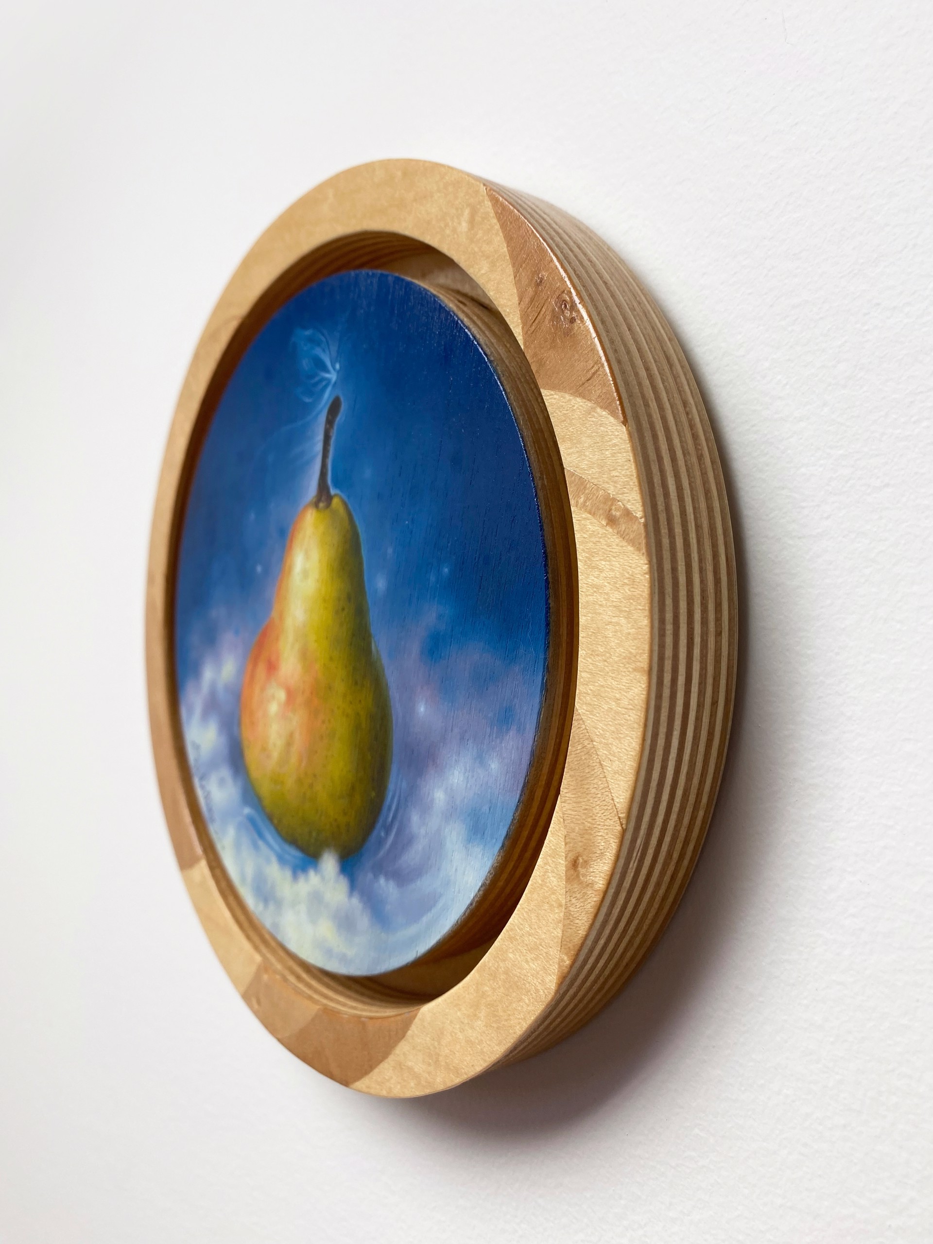 A pear floats in a dreamy blue sky with a butterfly hovering above it.