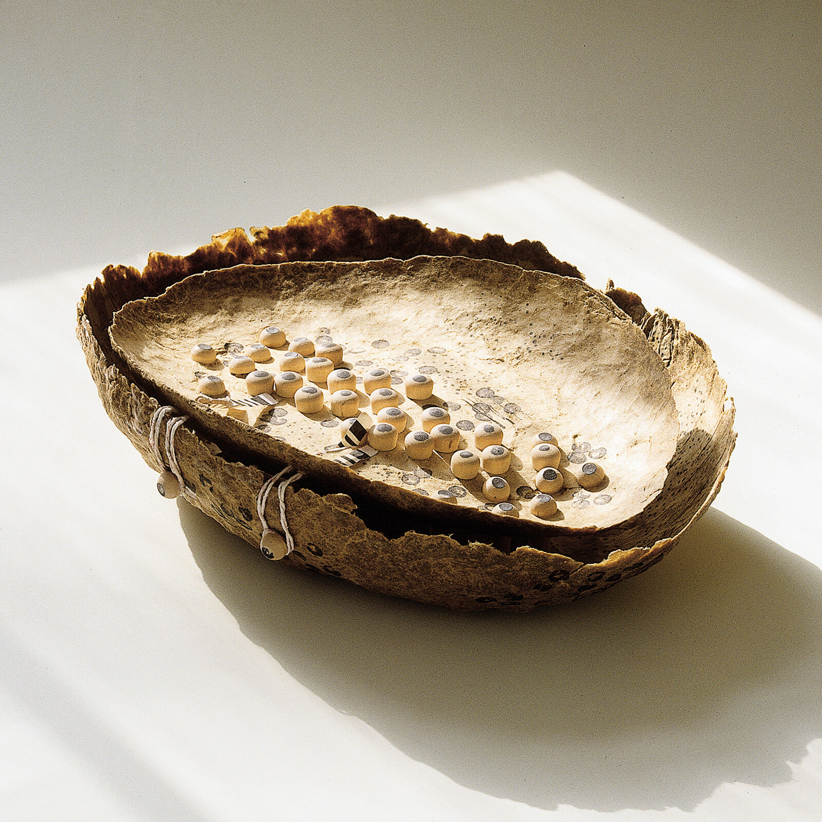 A wooden bowl filled with lots of small white beads.