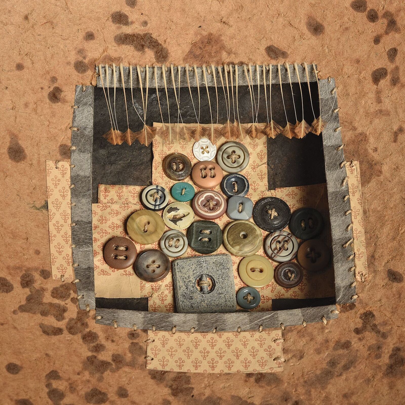 A rustic bowl with a collage of buttons and fabric inside.
