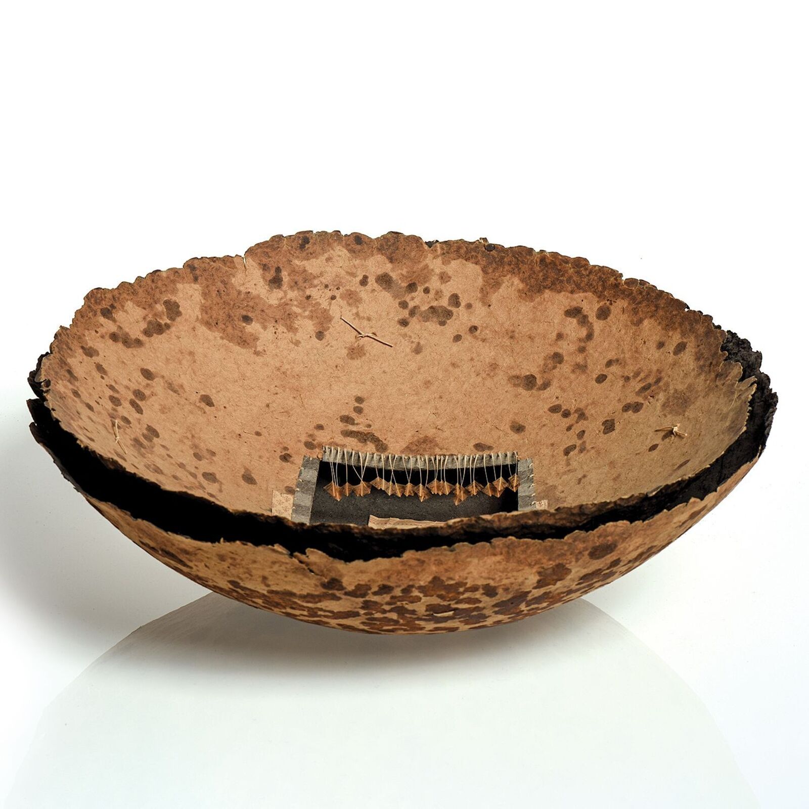 A rustic bowl with a collage of buttons and fabric inside.