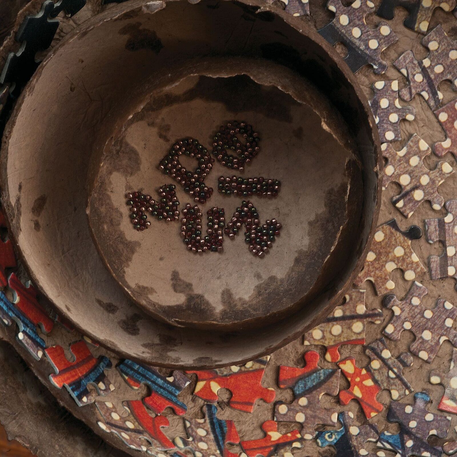 A nested sculpture of organic bowls filled with puzzle pieces and small beads.