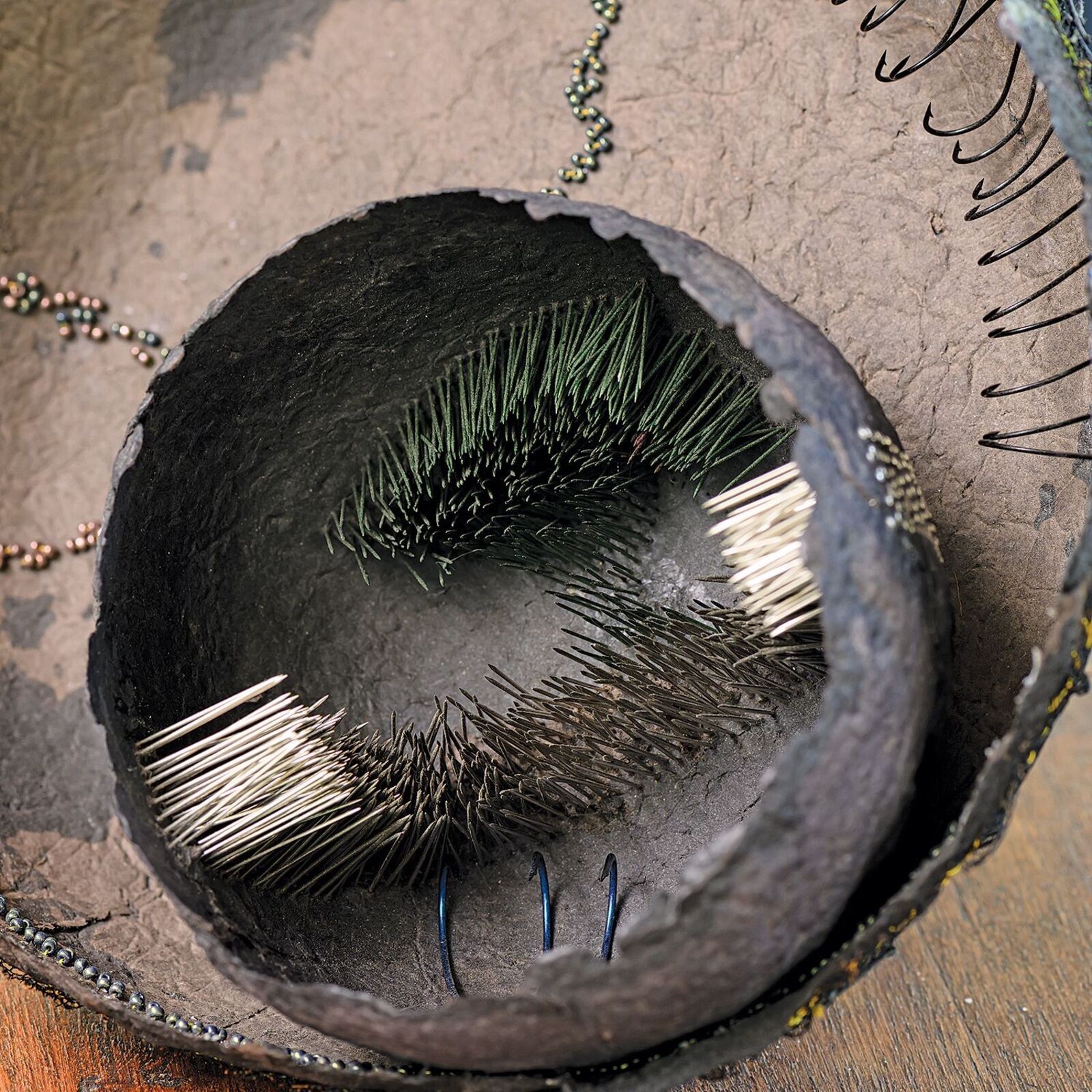 A high-angle view of a textured, bowl-like sculpture resting on a stone surface next to water.