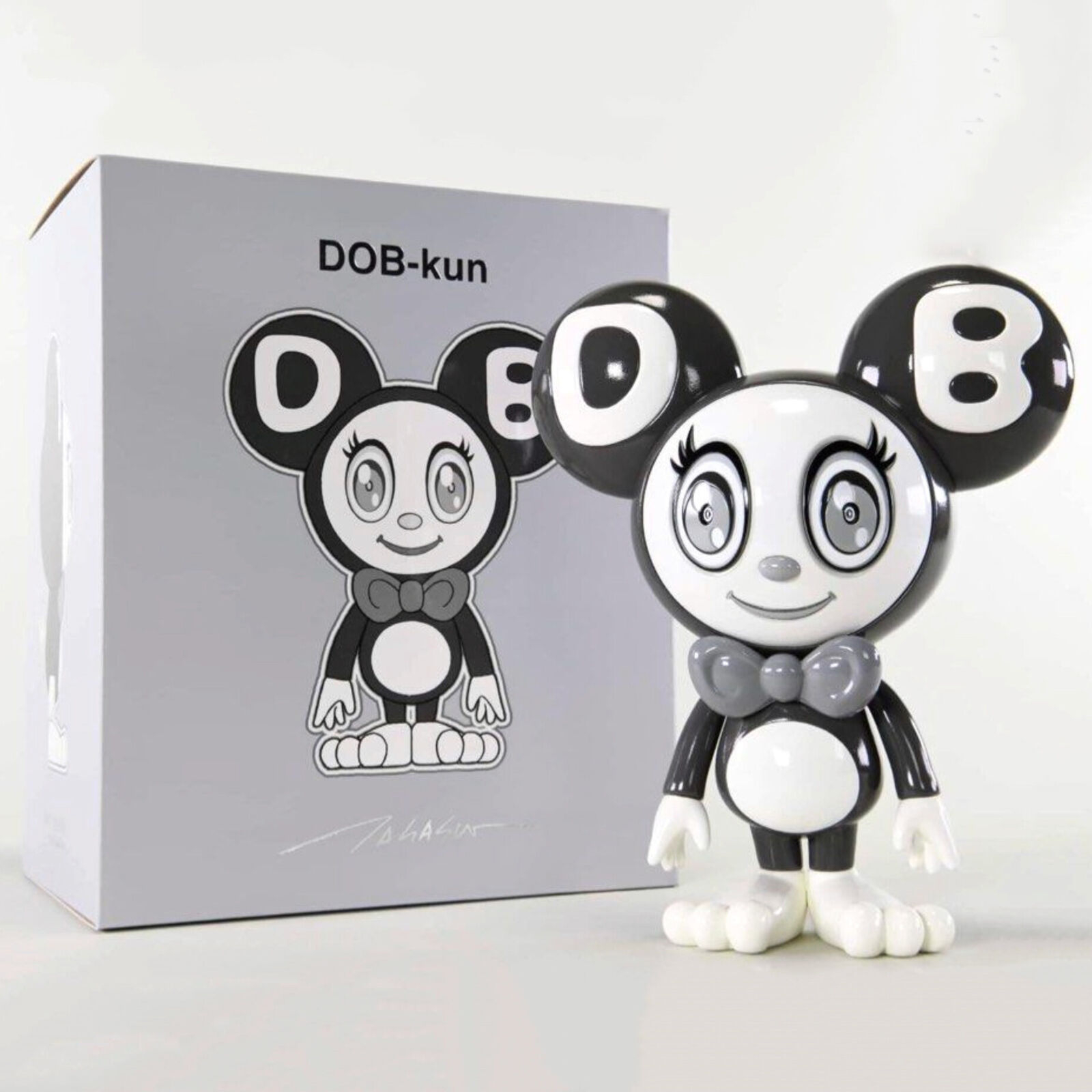 A black and white toy with a bow tie next to a box.