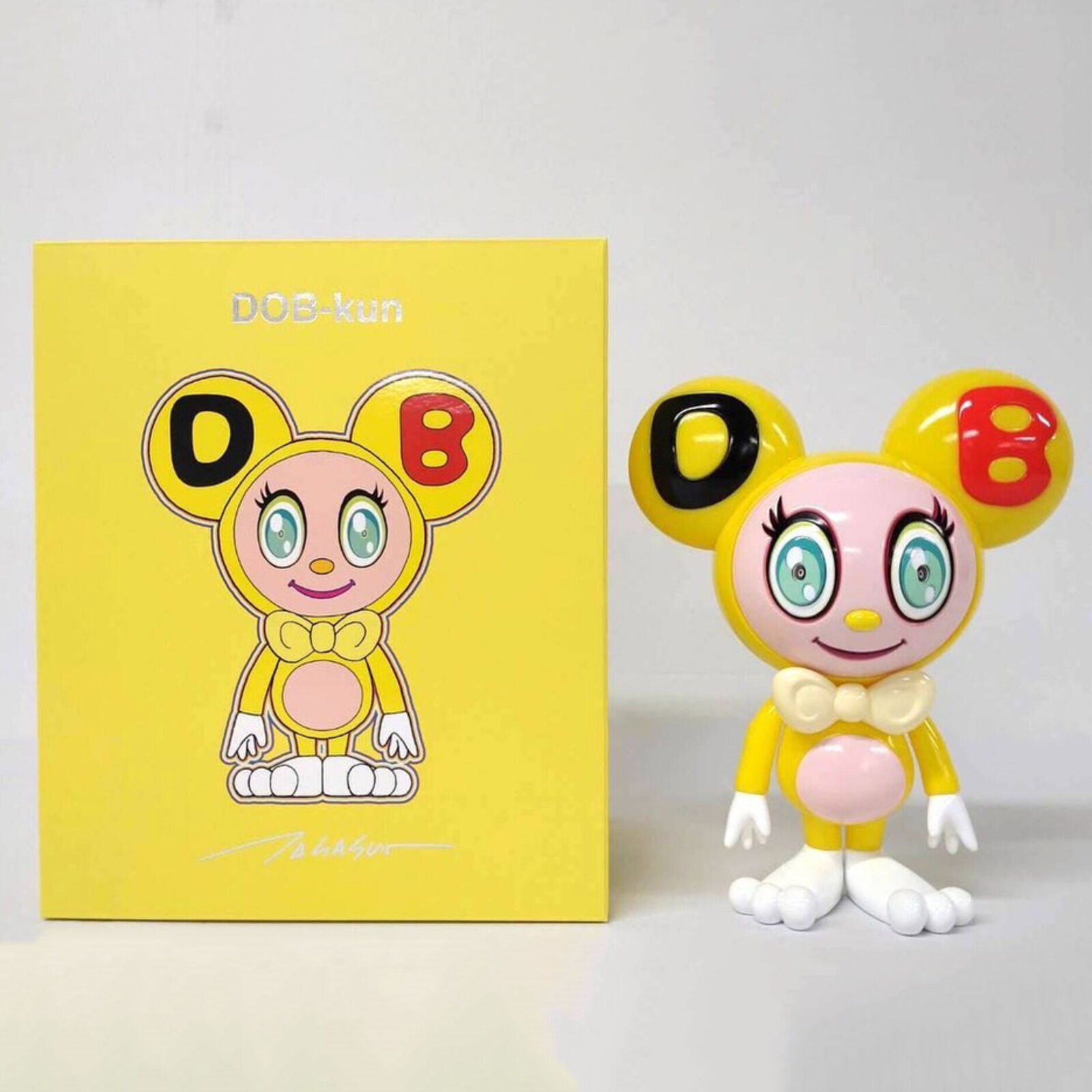 A yellow and white toy with a bow tie on it's head.