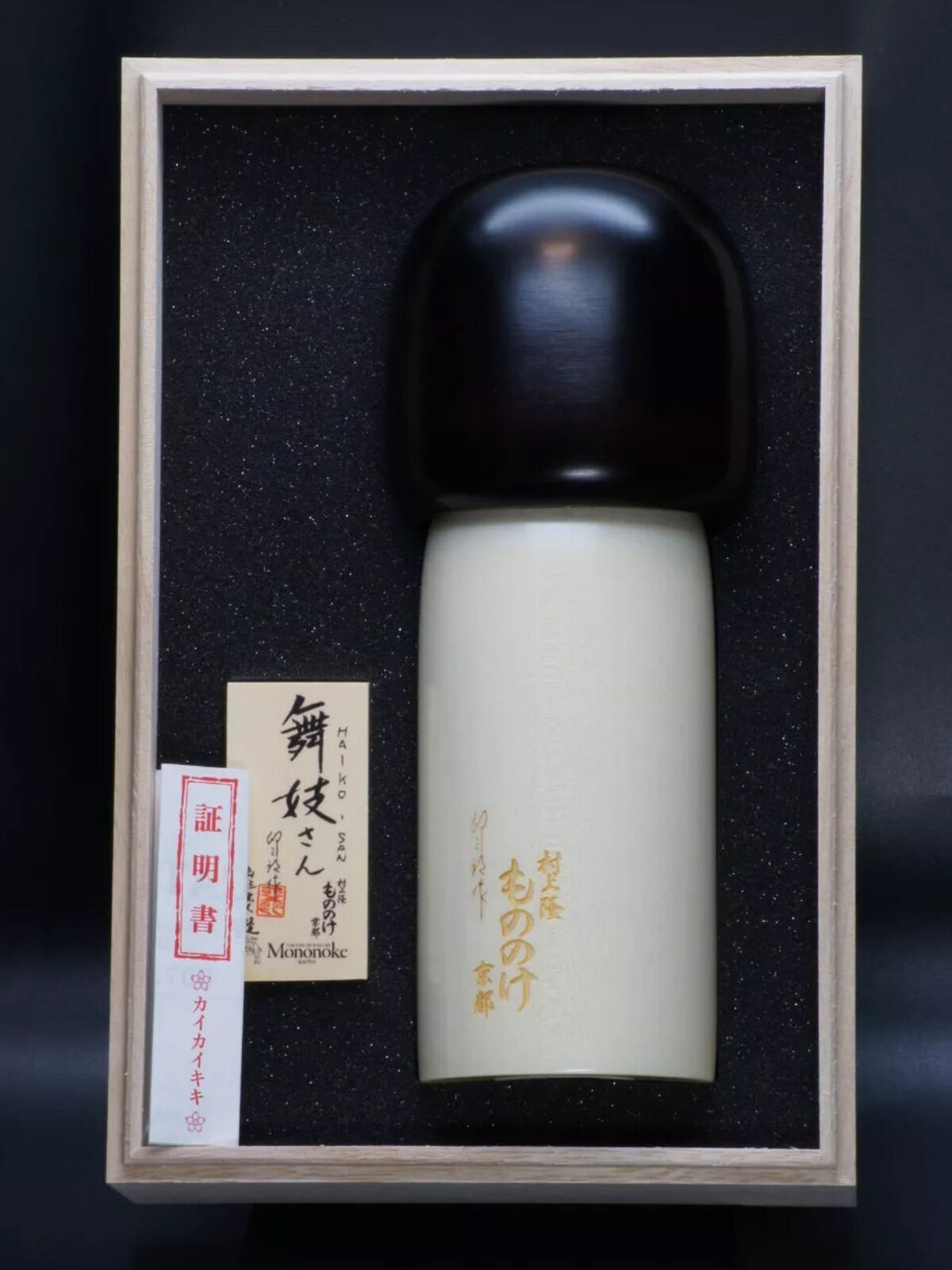 A wooden doll in a wooden box with a picture of a woman in a kimono.