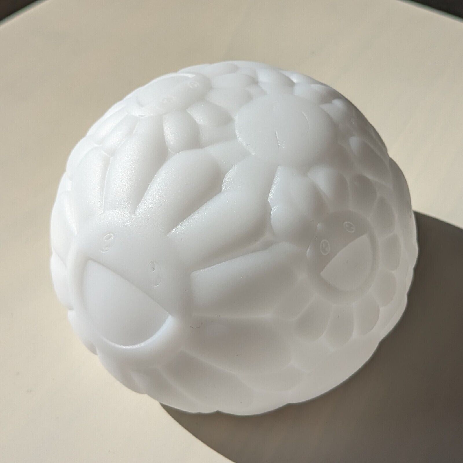 A white turtle shaped lamp on a black background.