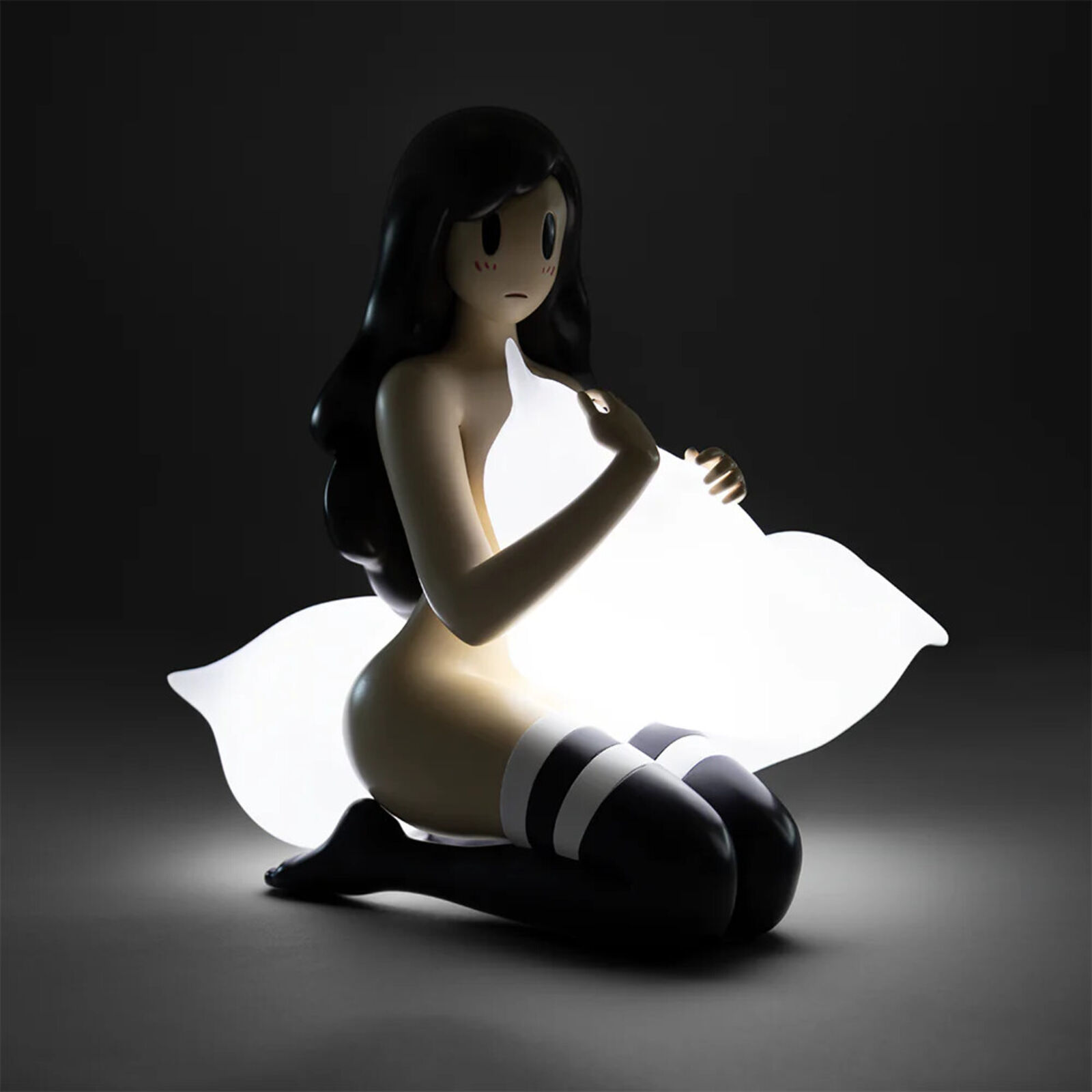 A figurine of a woman sitting on the ground holding a pillow.