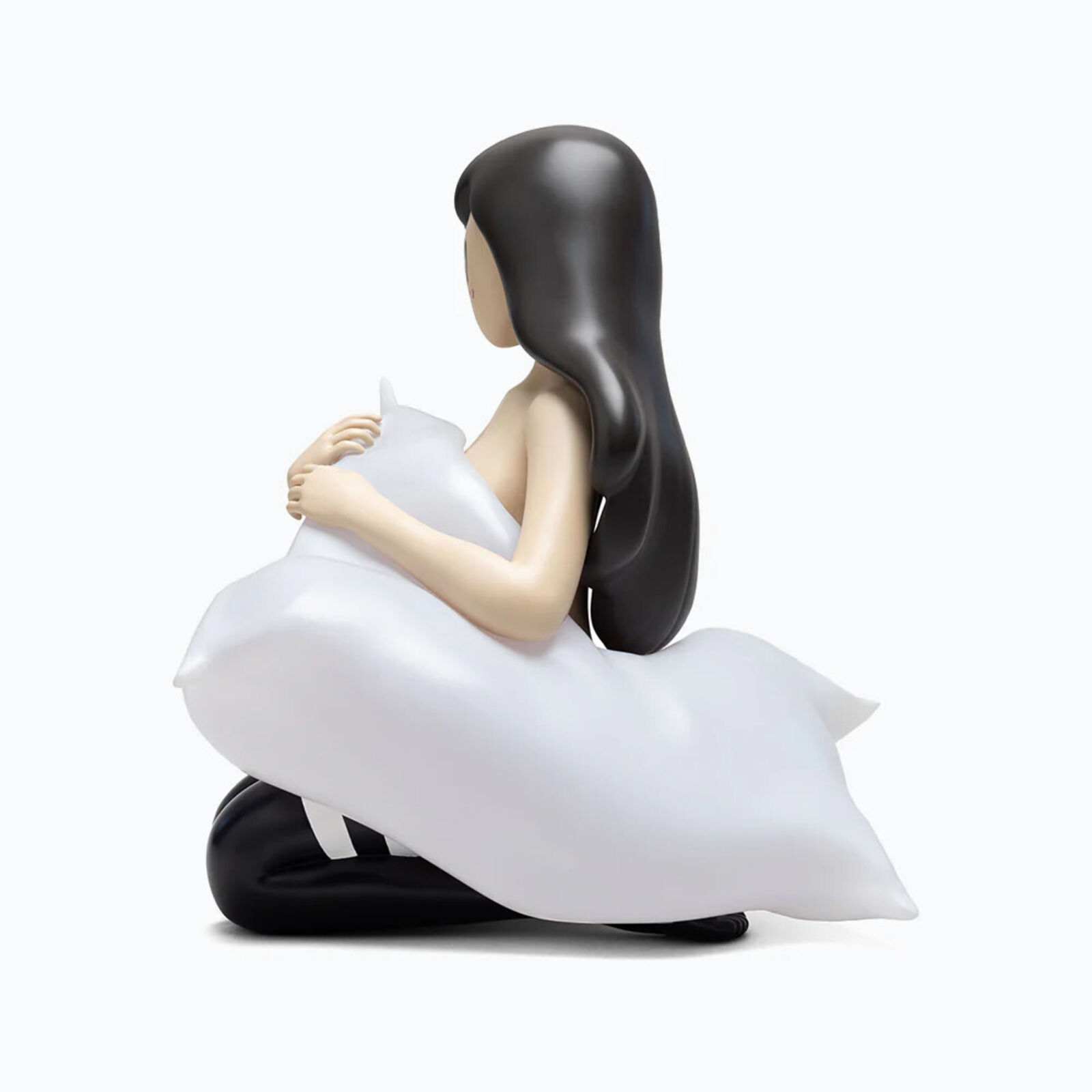 A figurine of a woman sitting on the ground holding a pillow.