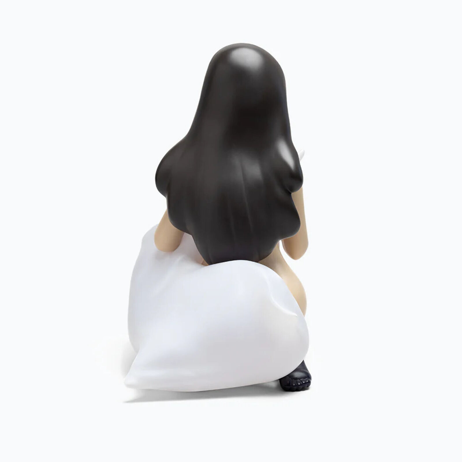 A figurine of a woman sitting on the ground holding a pillow.