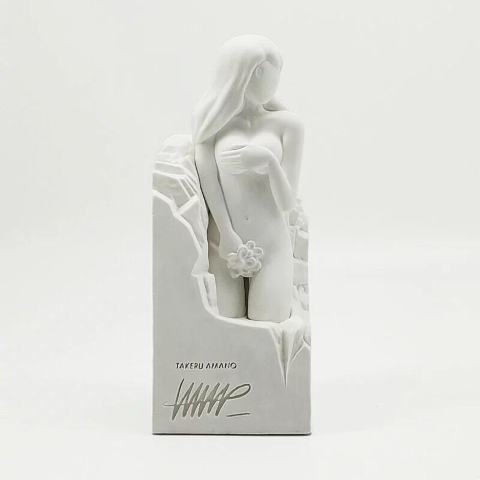 A white statue of a woman sitting on top of a box.