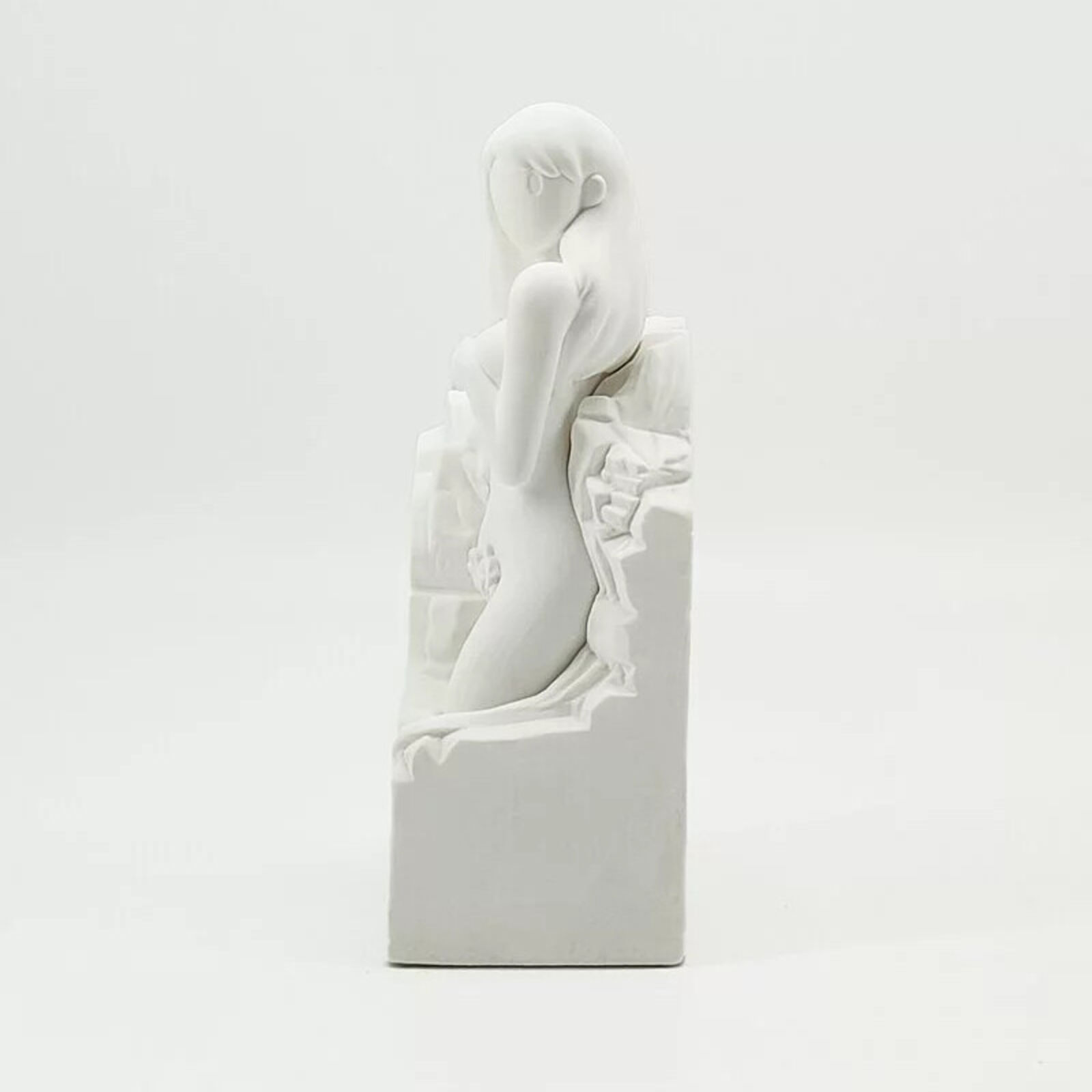 A white statue of a woman sitting on top of a box.