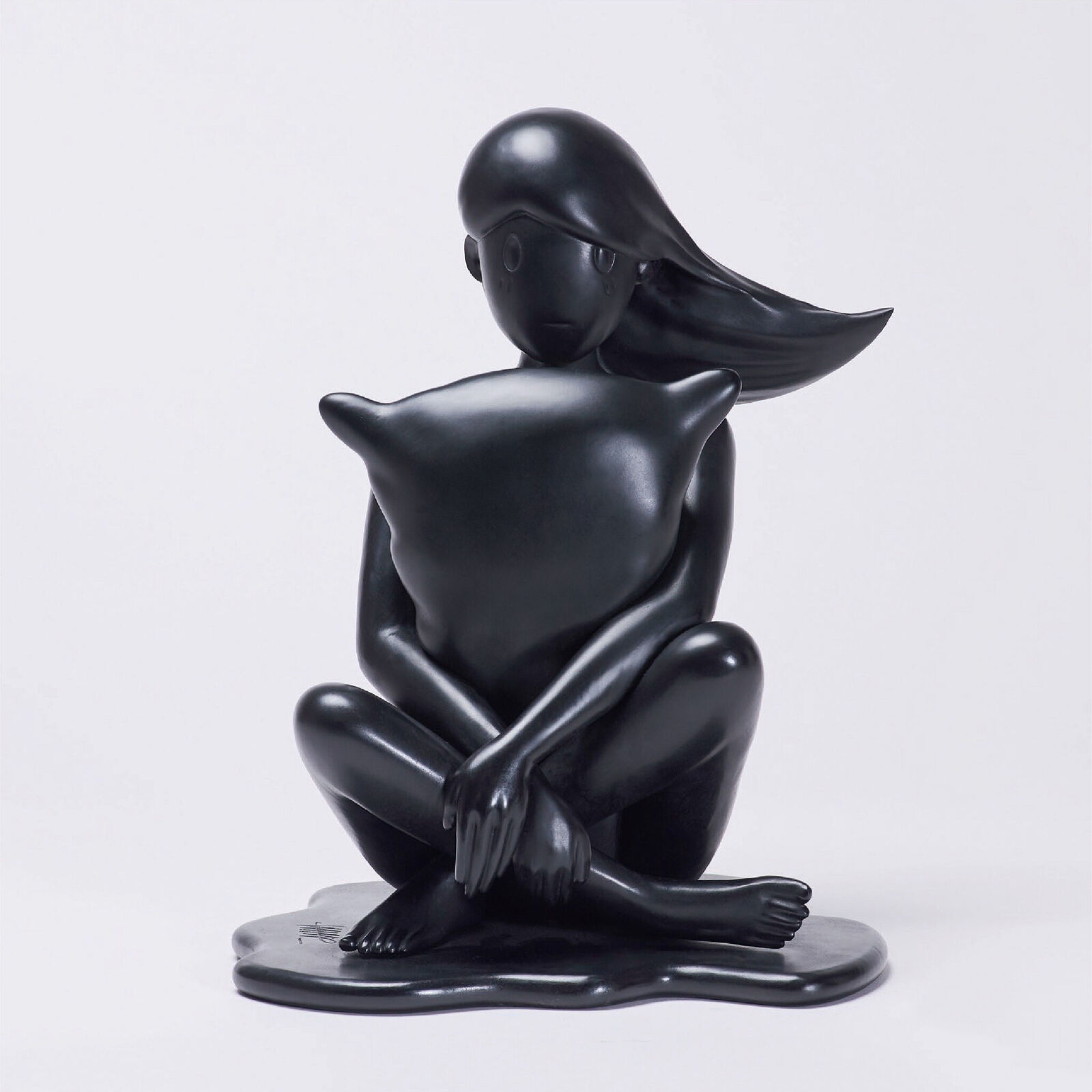 A black sculpture of a woman sitting on the ground.