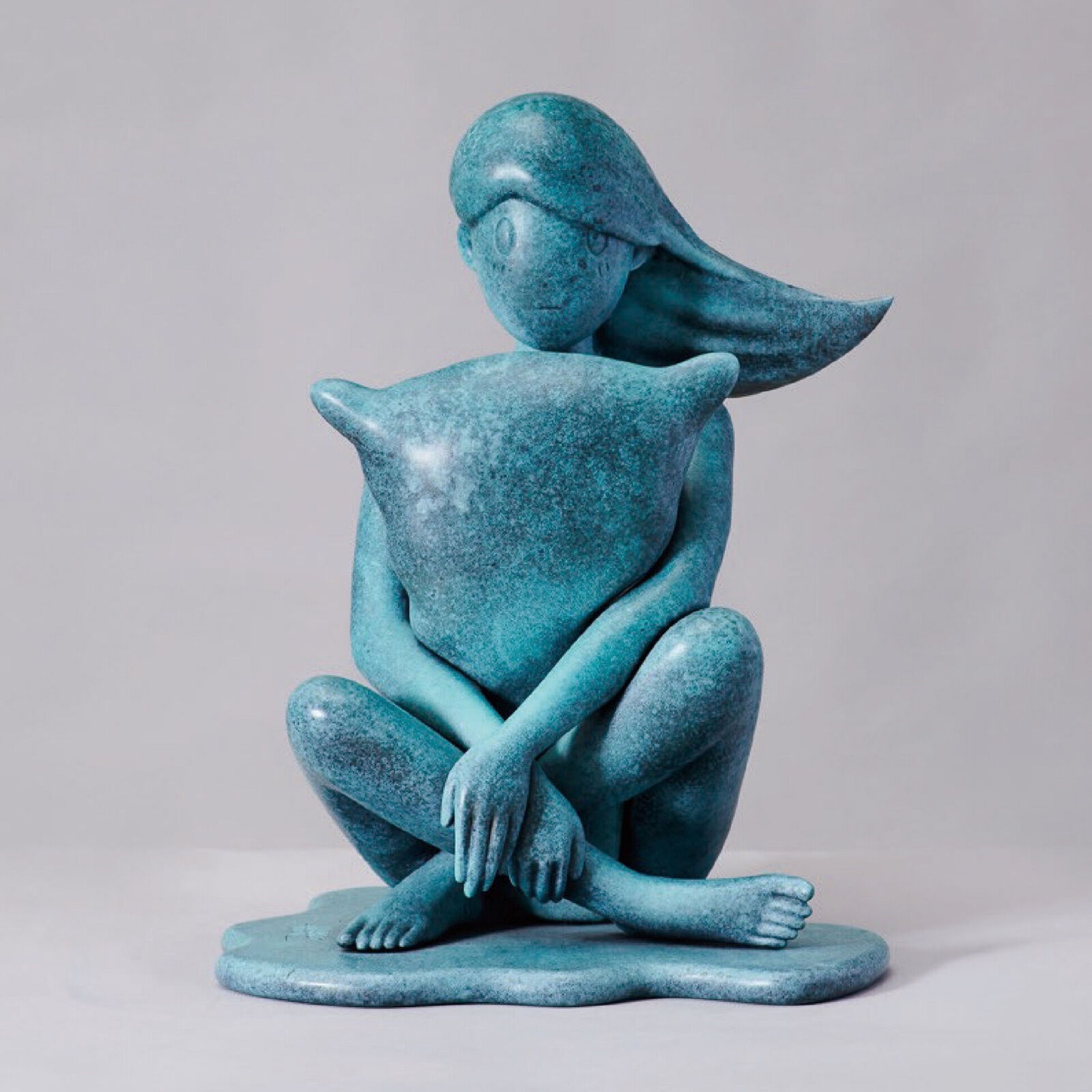 A statue of a woman sitting on the ground with her head in her hands.