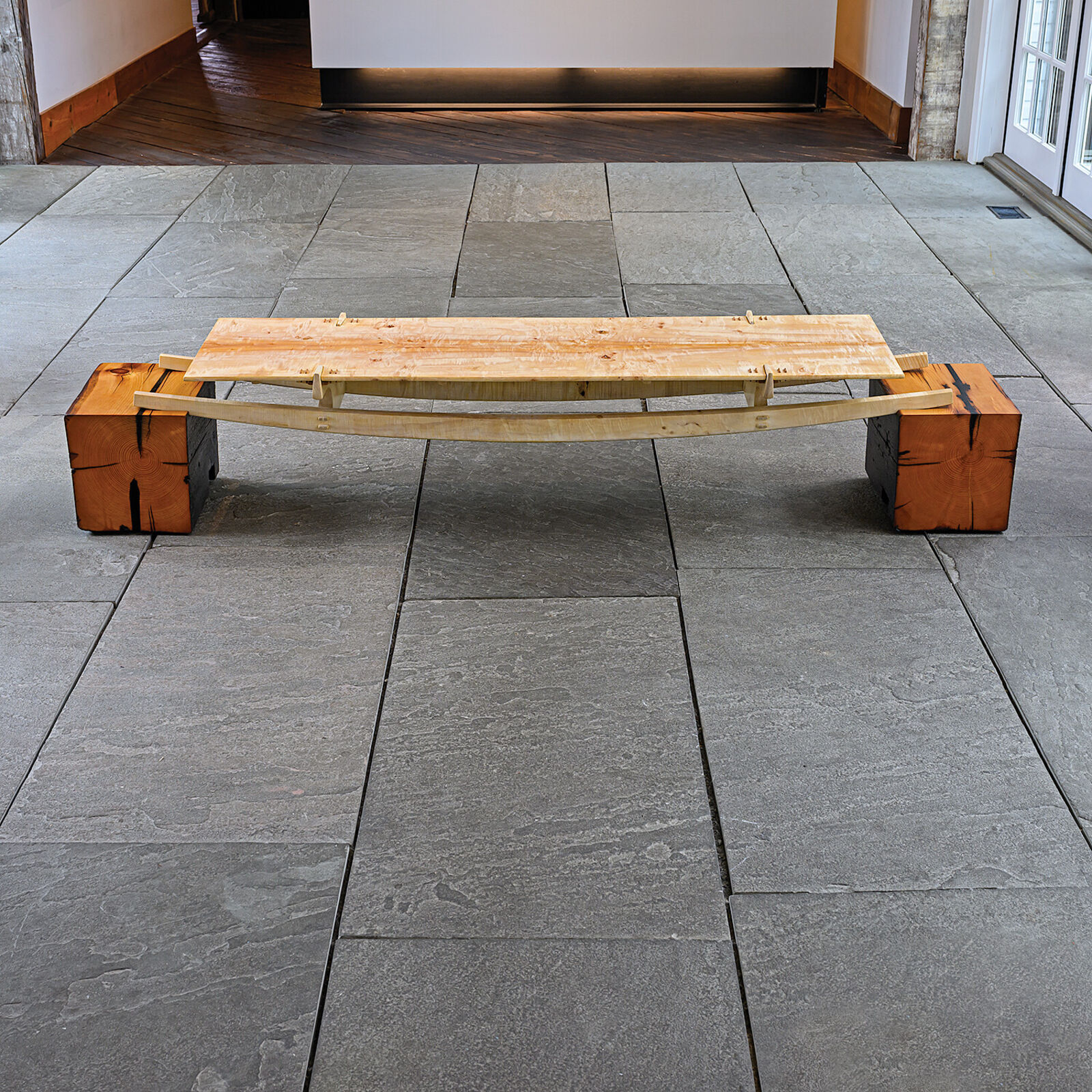 A minimalist wooden bench with a sleek design and natural wood tones.