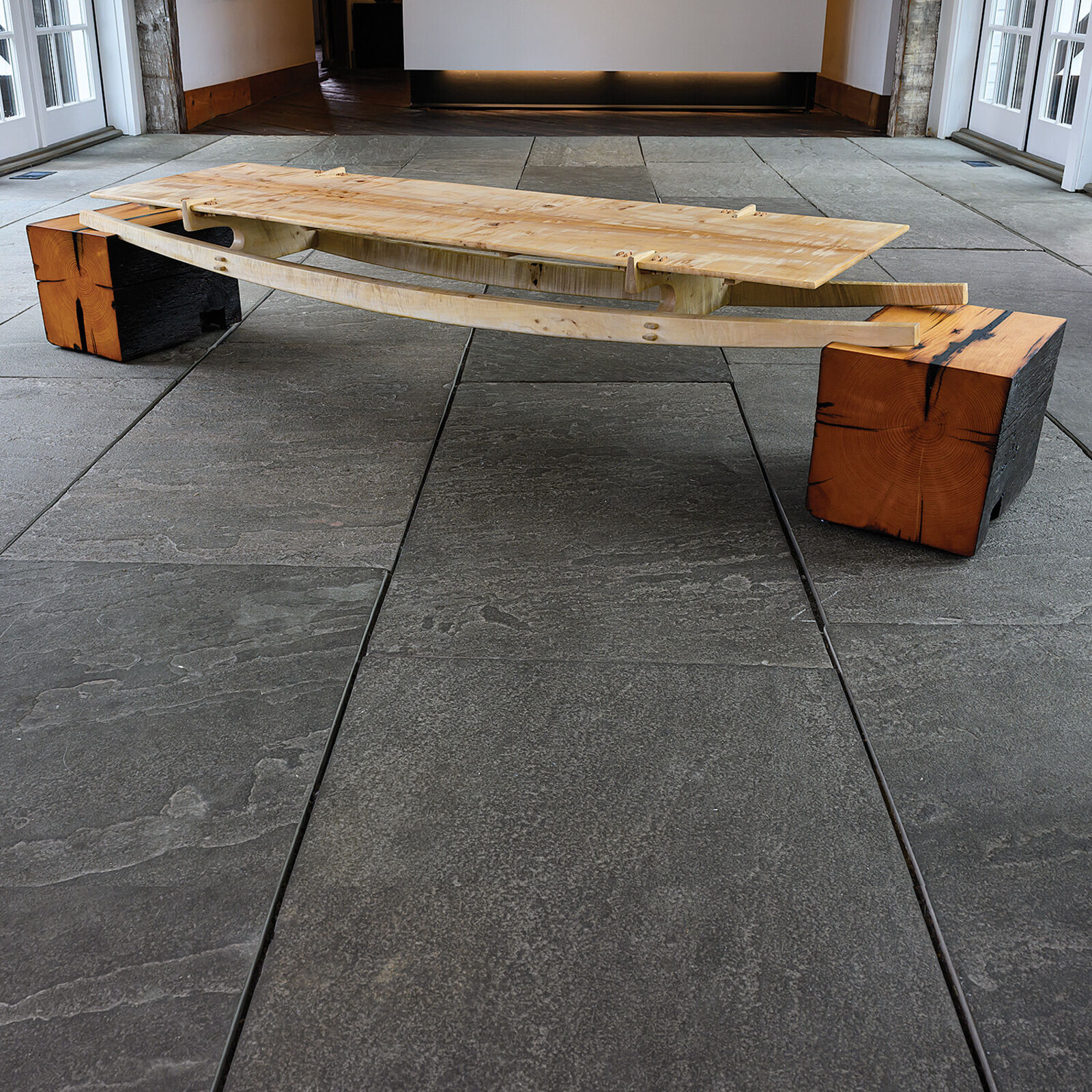 A minimalist wooden bench with a sleek design and natural wood tones.