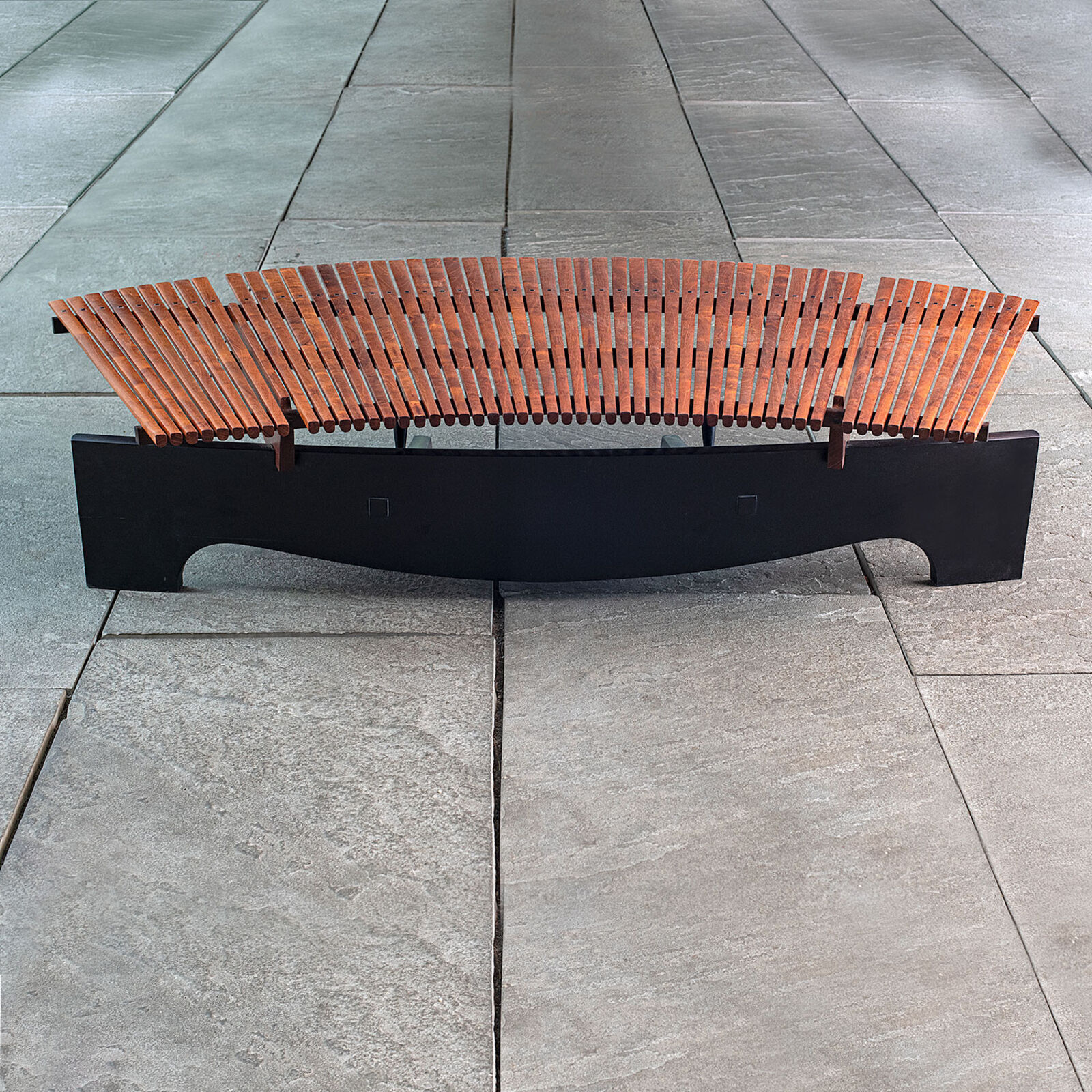 A modern wooden coffee table with a curved slatted top and sculpted black legs.