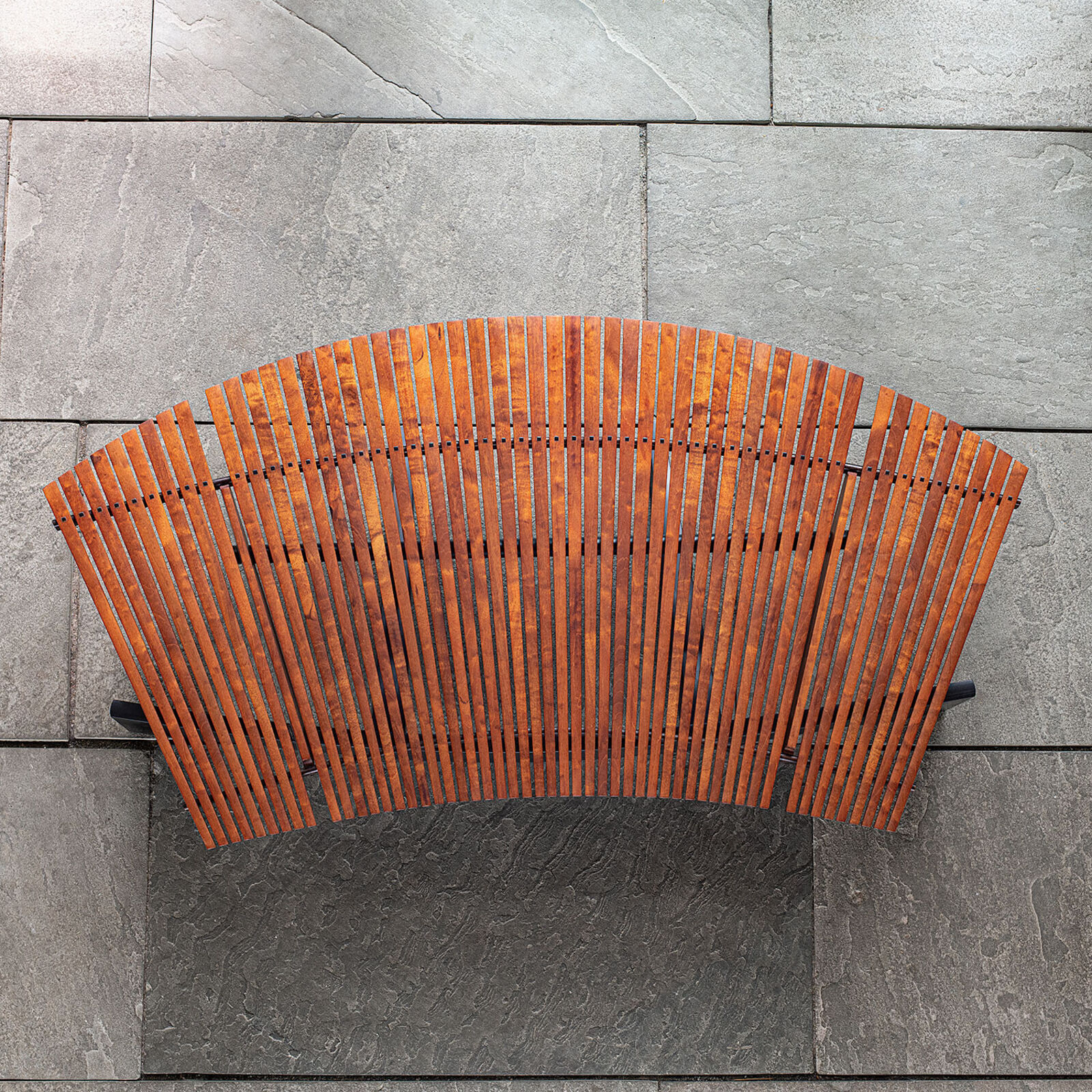 A modern wooden coffee table with a curved slatted top and sculpted black legs.