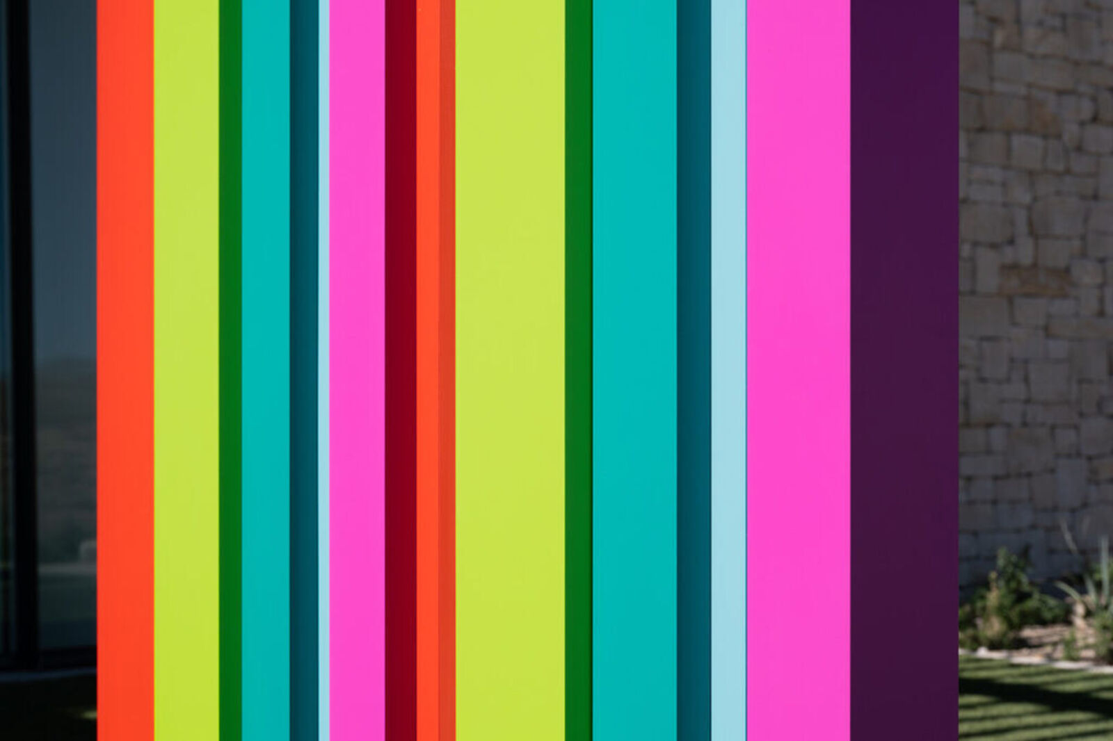 A tall, colorful striped sculpture stands in a desert landscape.