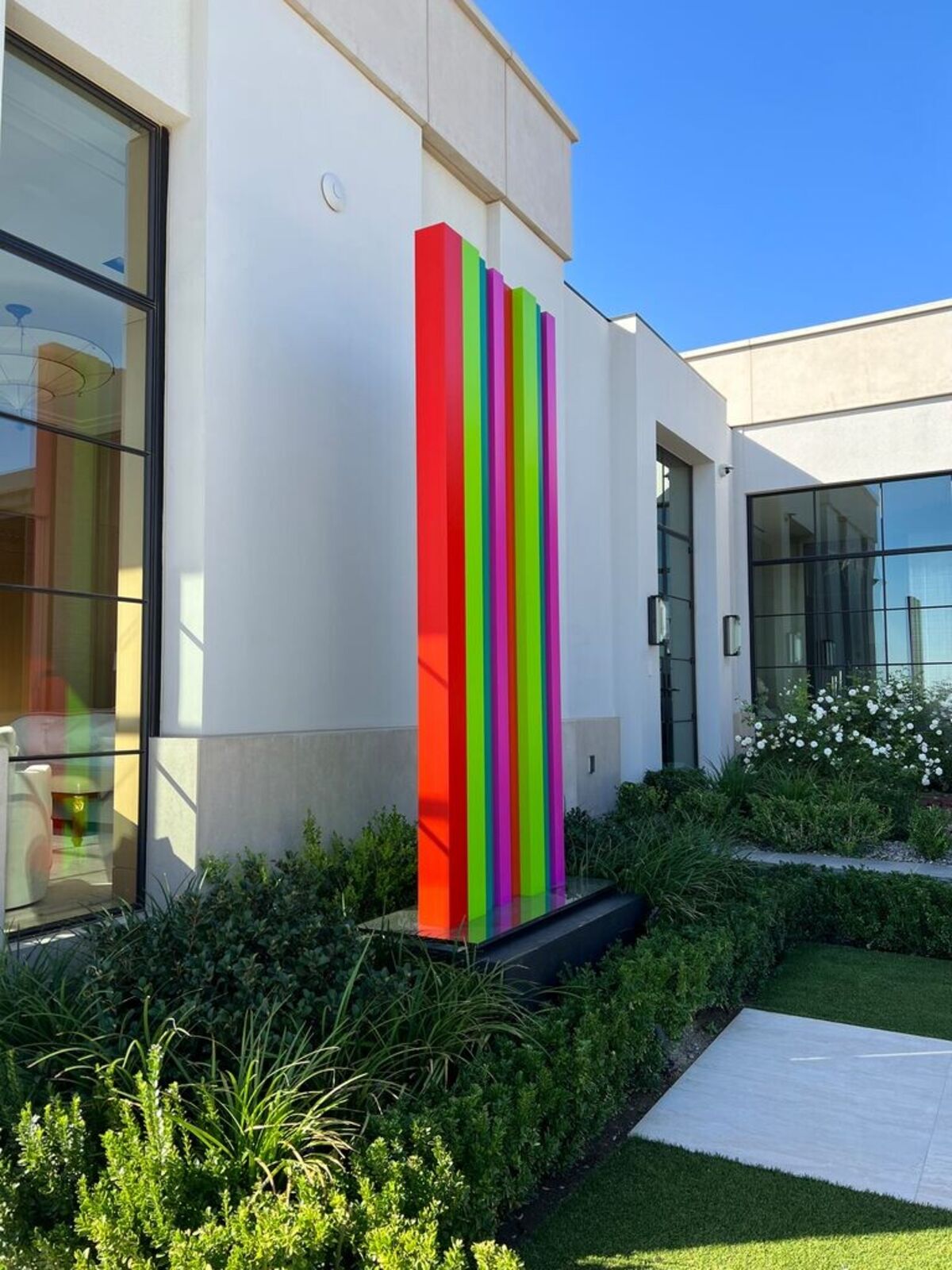 A tall, colorful striped sculpture stands in a desert landscape.