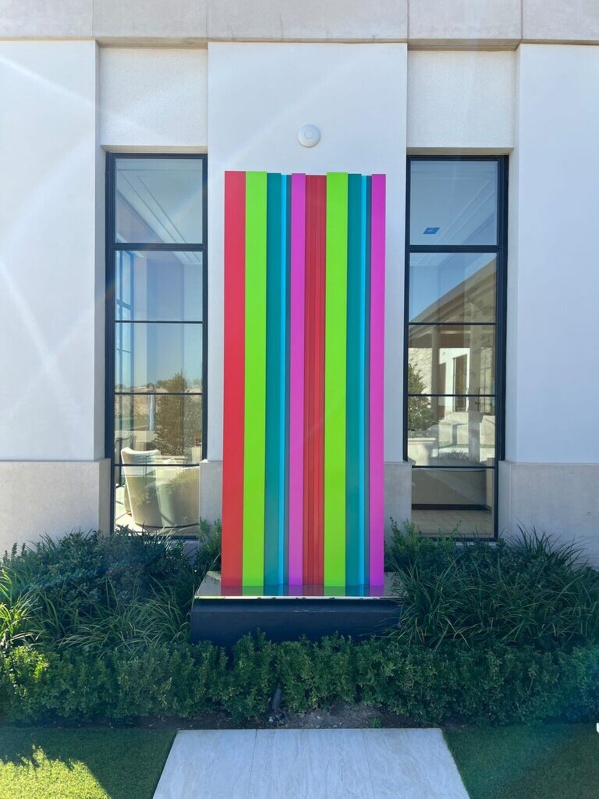 A tall, colorful striped sculpture stands in a desert landscape.
