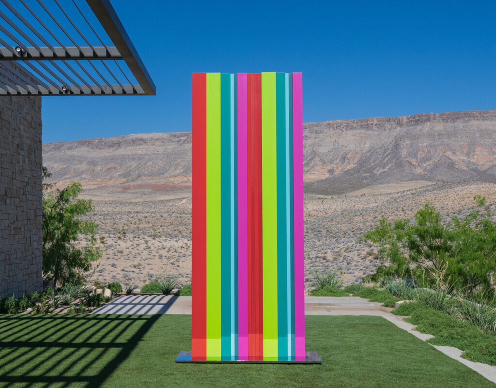 A tall, colorful striped sculpture stands in a desert landscape.