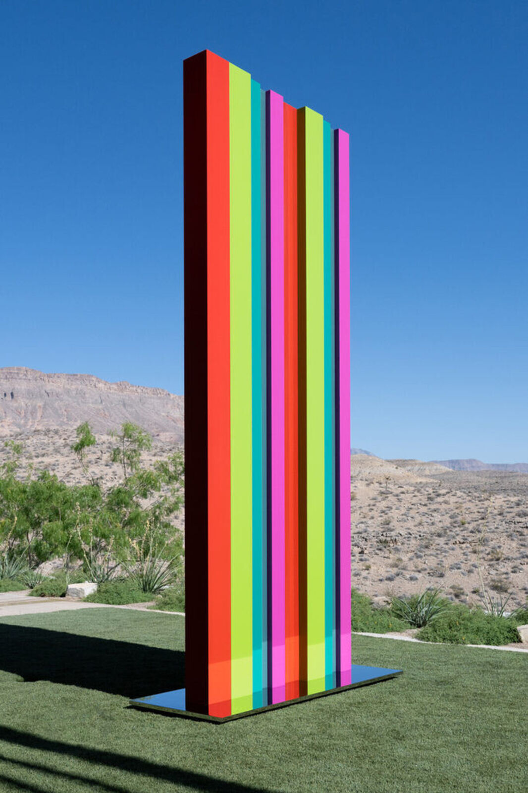 A tall, colorful striped sculpture stands in a desert landscape.