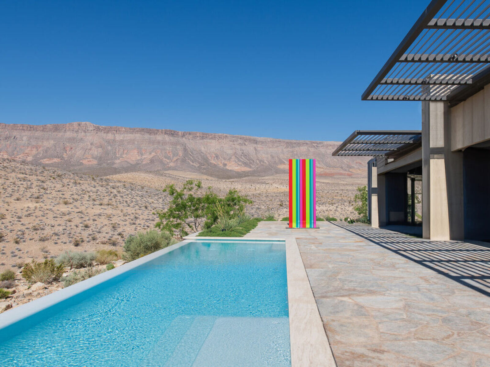 A tall, colorful striped sculpture stands in a desert landscape.