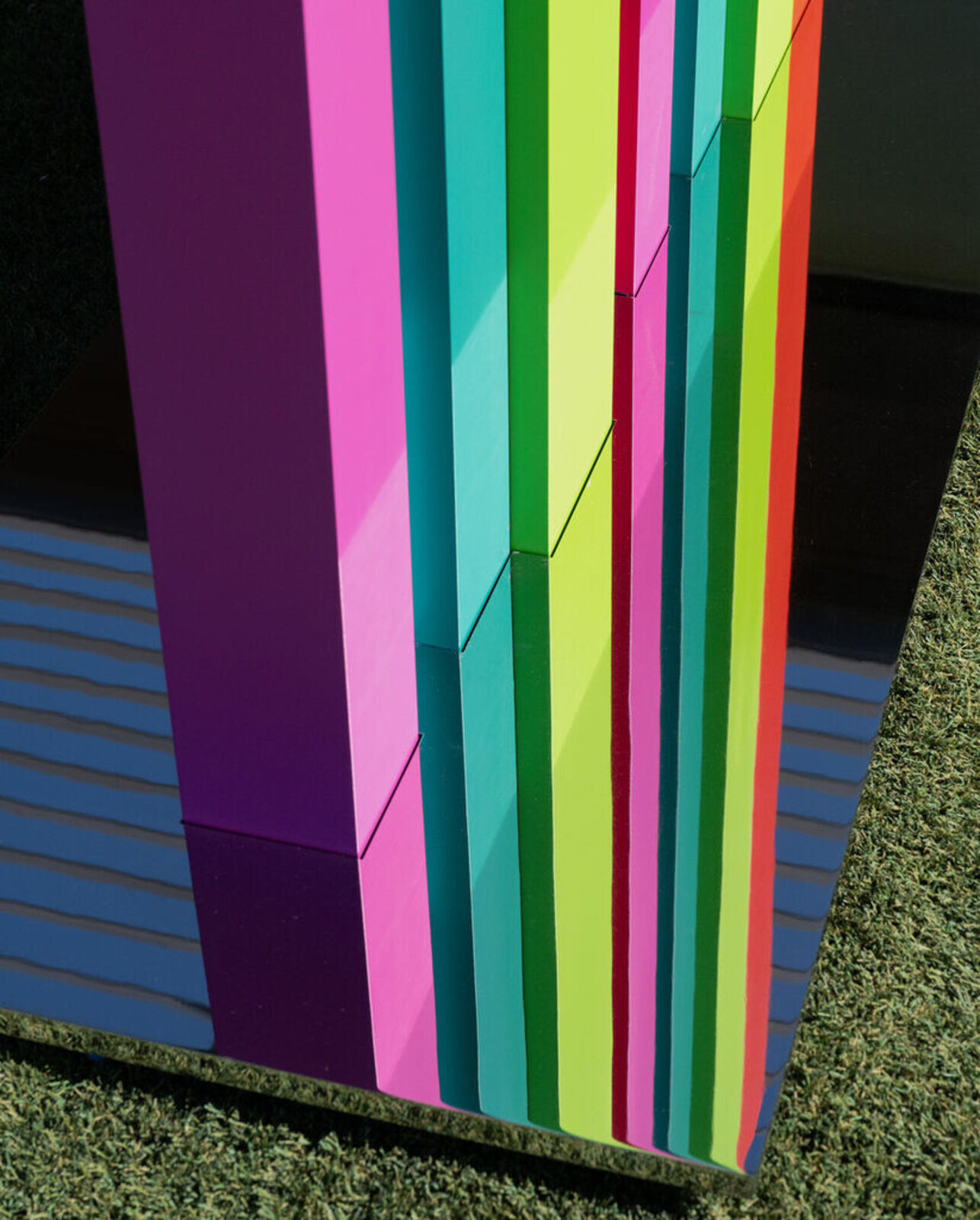 A tall, colorful striped sculpture stands in a desert landscape.
