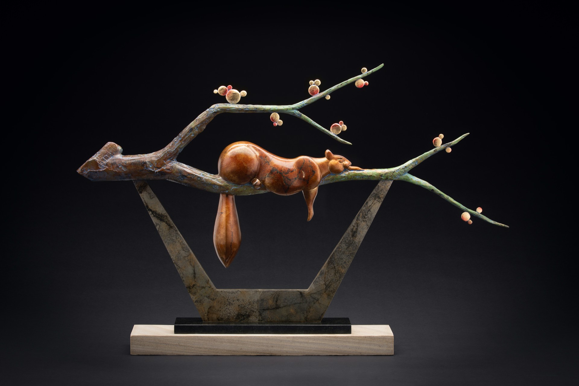 A bronze sculpture of a squirrel on a tree branch.