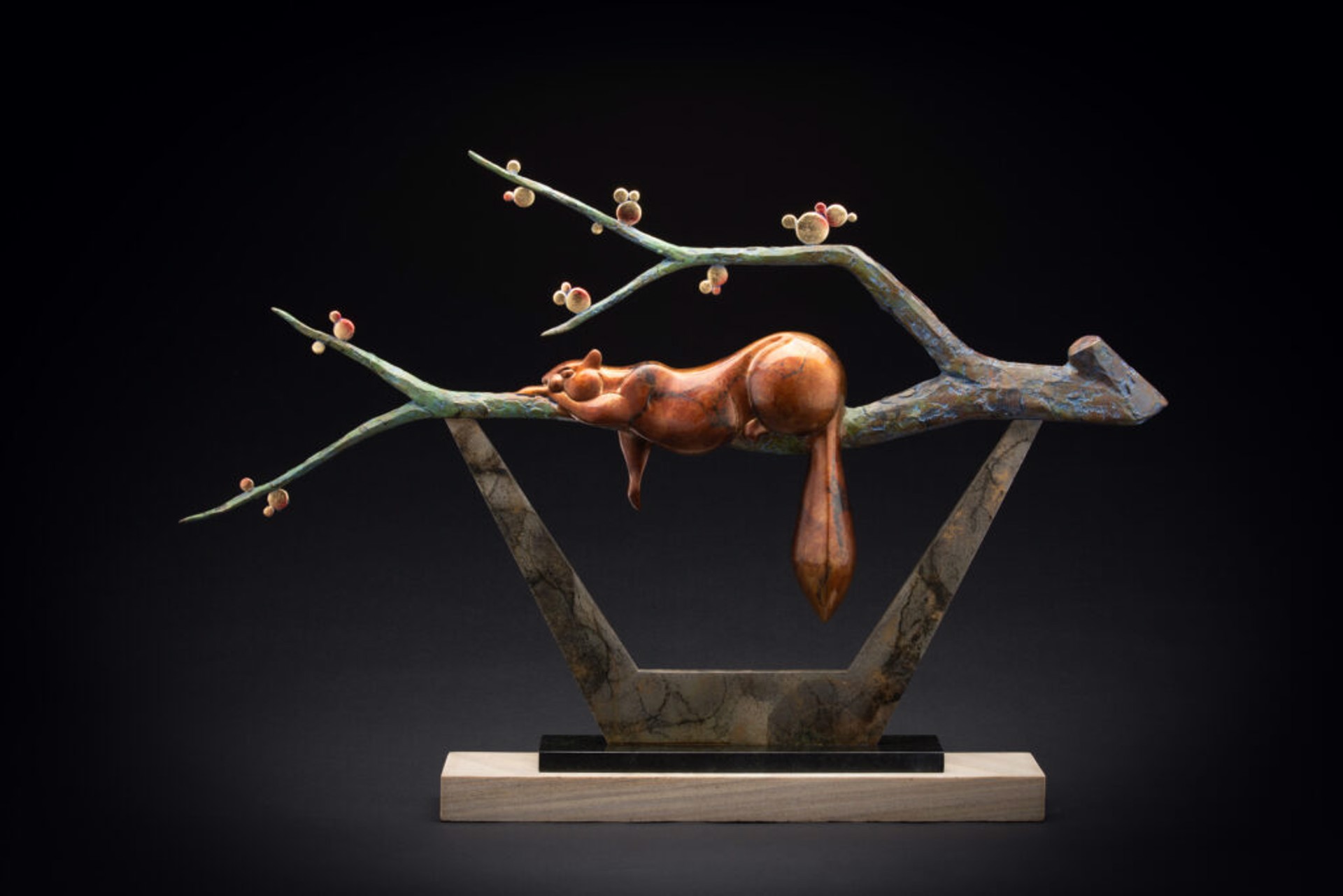 A bronze sculpture of a squirrel on a tree branch.