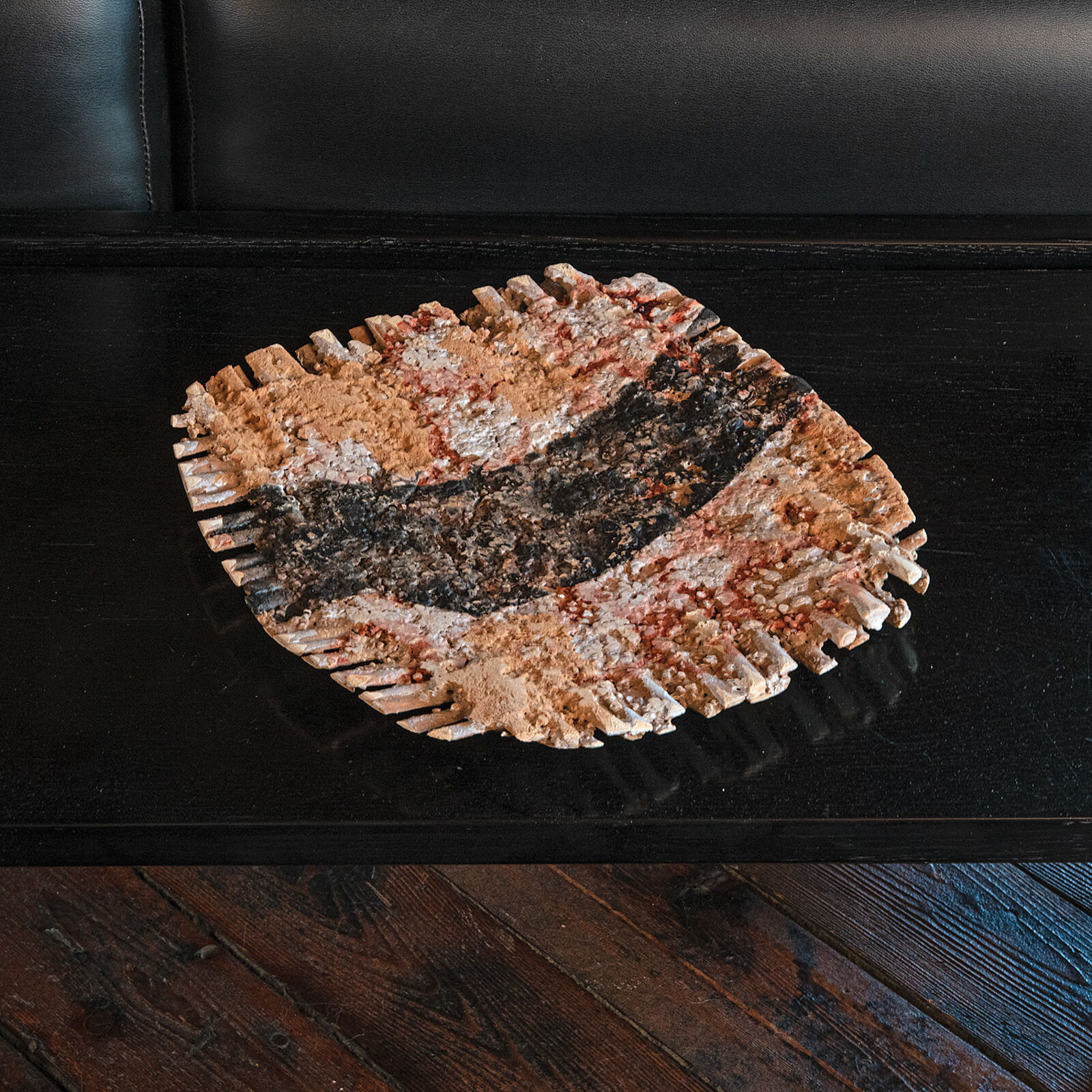 "A rustic, textured bowl with a dark central stripe sits on a glossy black surface."