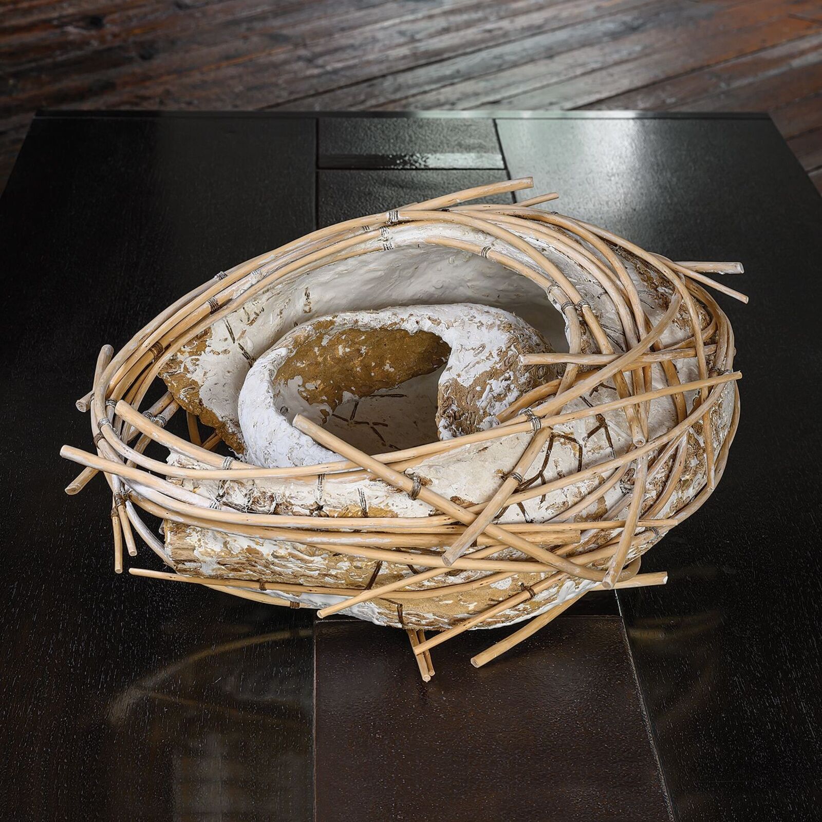 A rustic sculpture resembling a bird's nest made from woven bamboo and textured clay.