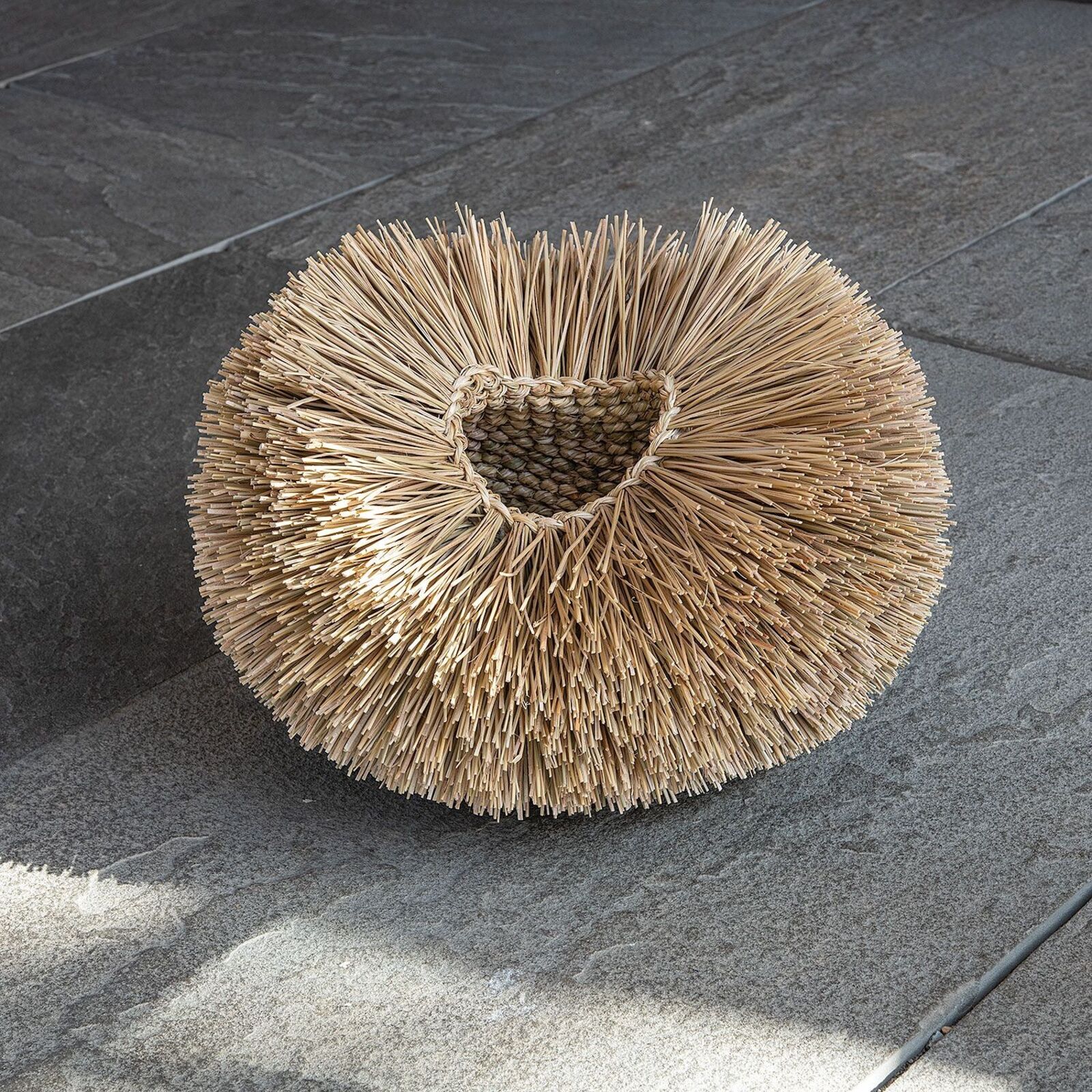 A close-up of a woven basket interior with radiating straw spokes.