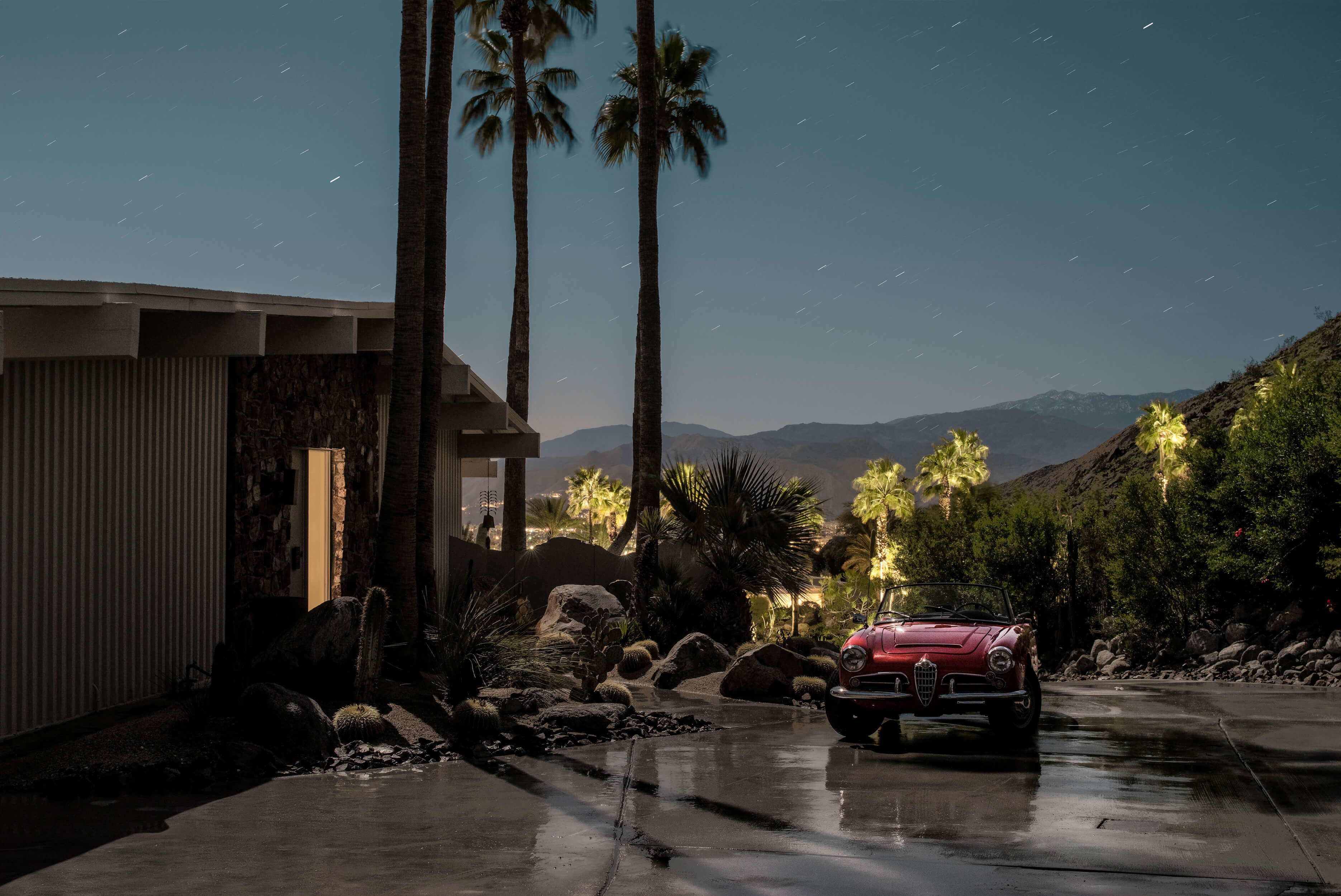 A red car parked in front of a house at night.