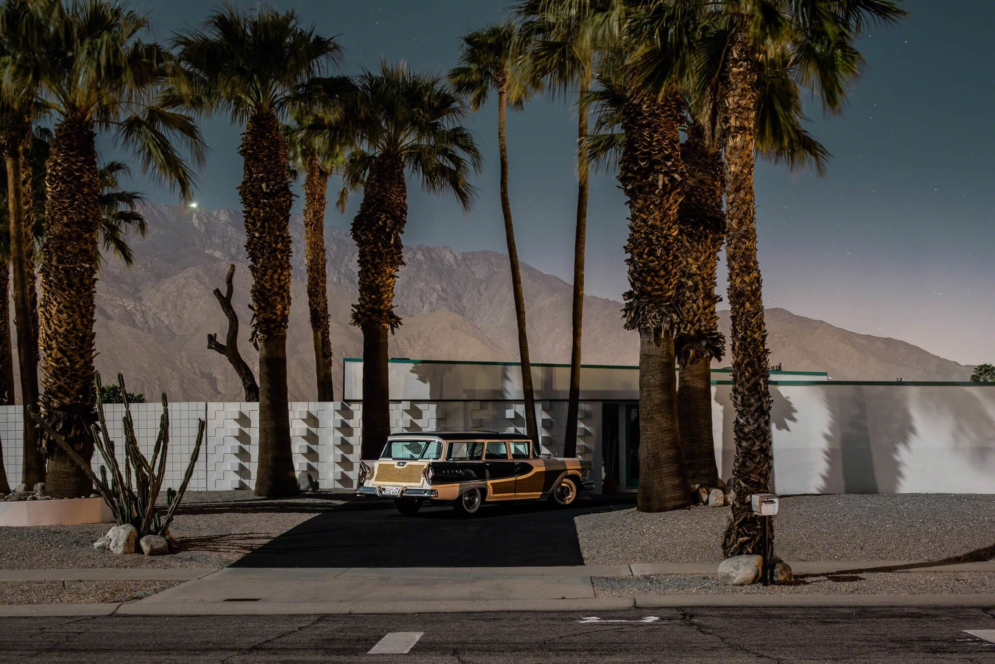 A car parked in front of a building with palm trees.