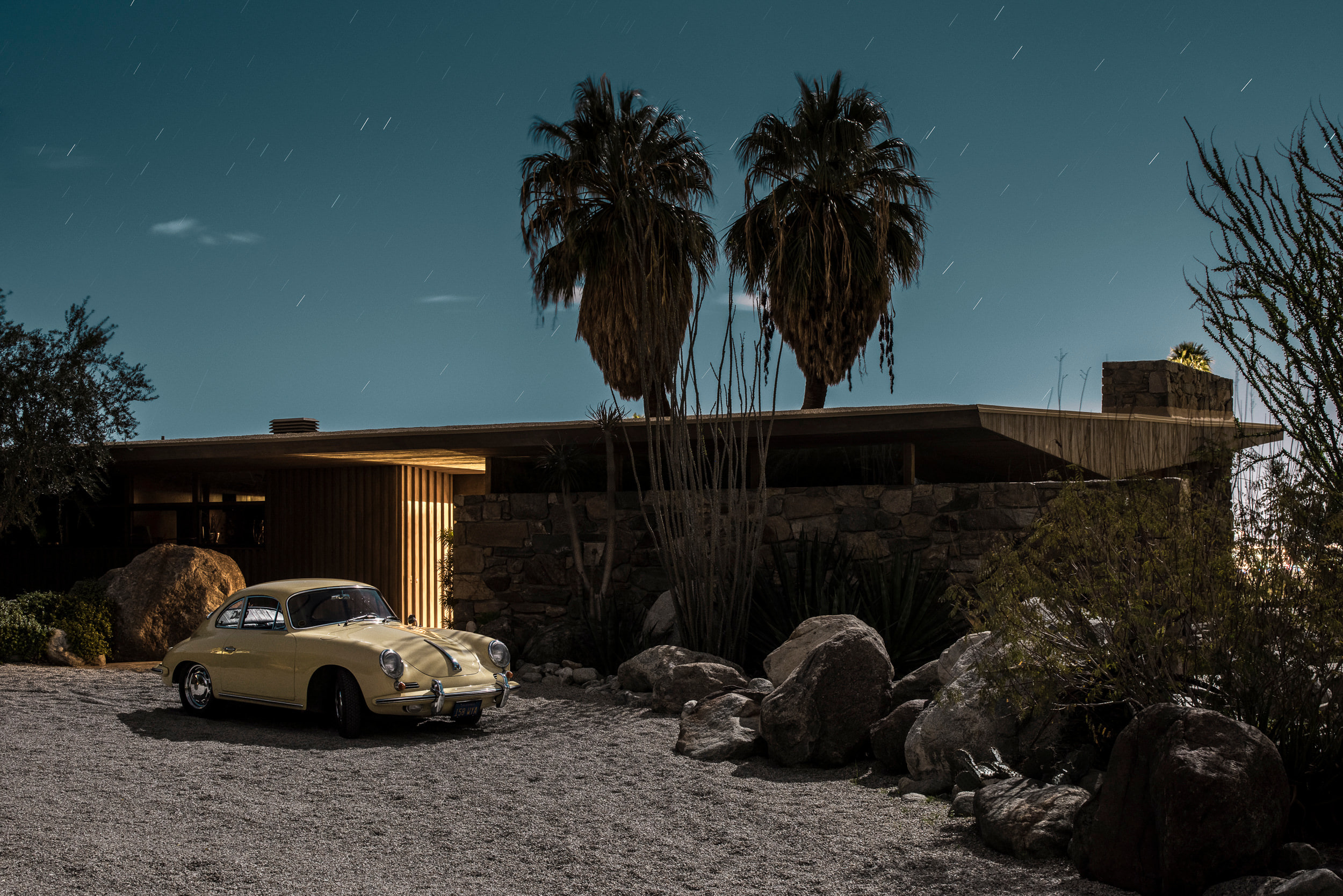 A car parked in front of a house with palm trees.