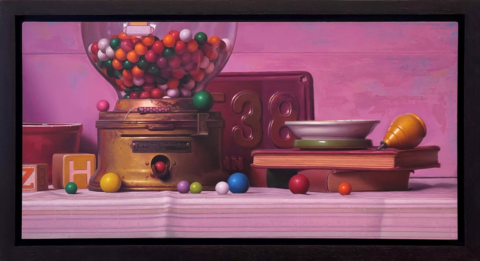A colorful still life featuring a vintage gumball machine, books, and scattered spheres against a soft pink backdrop.