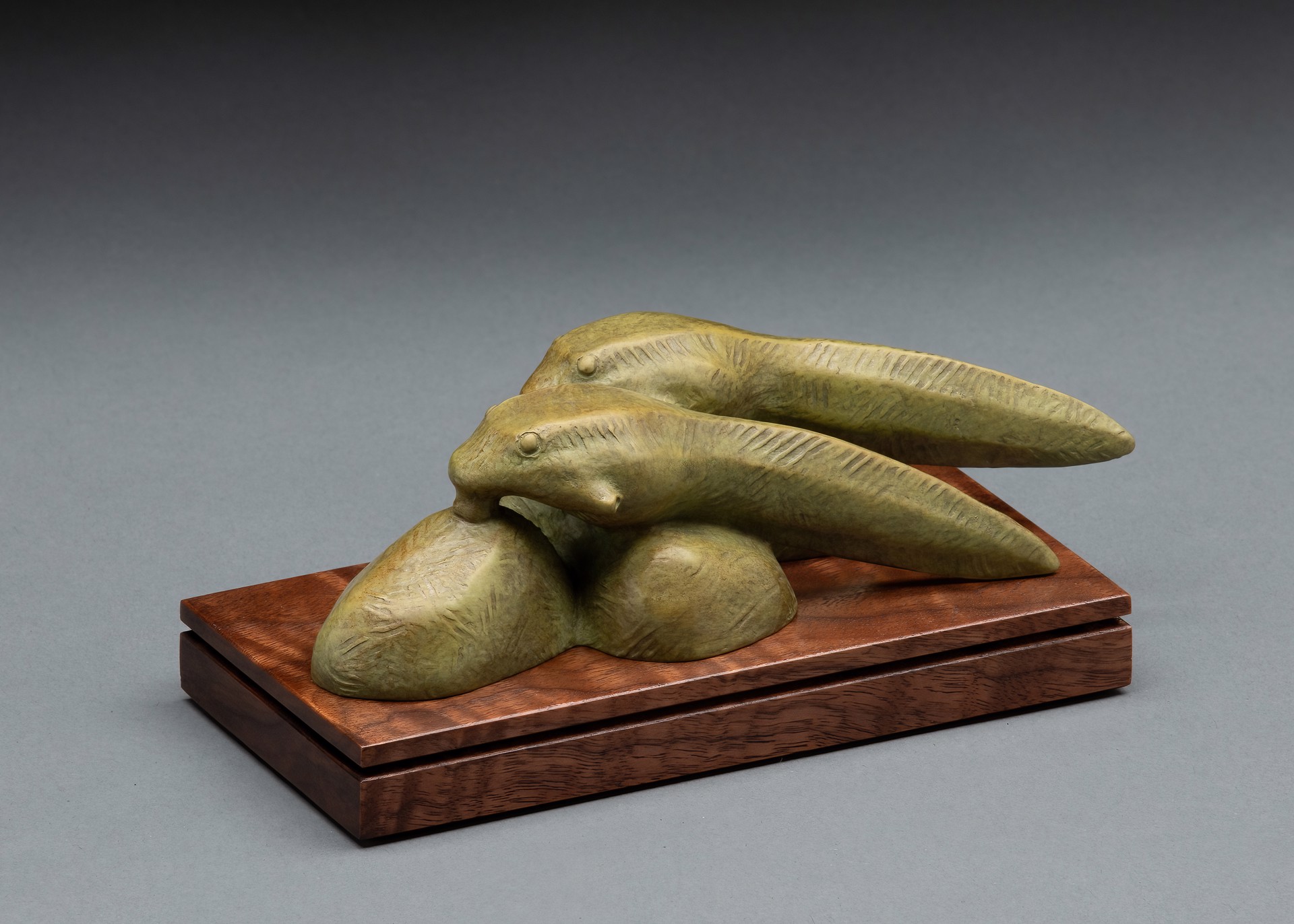 A sculpture of two fish on a wooden base.