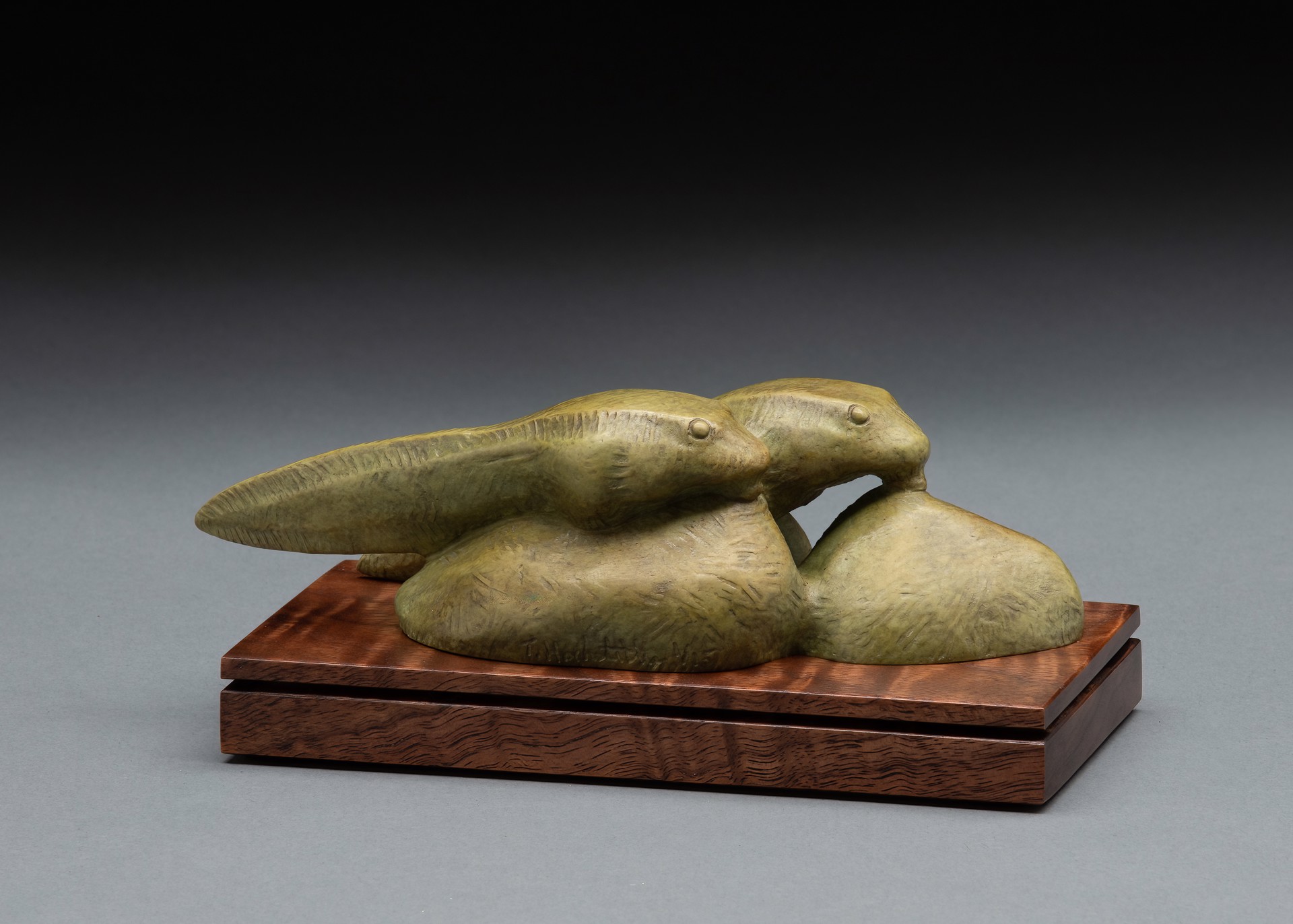 A sculpture of two fish on a wooden base.