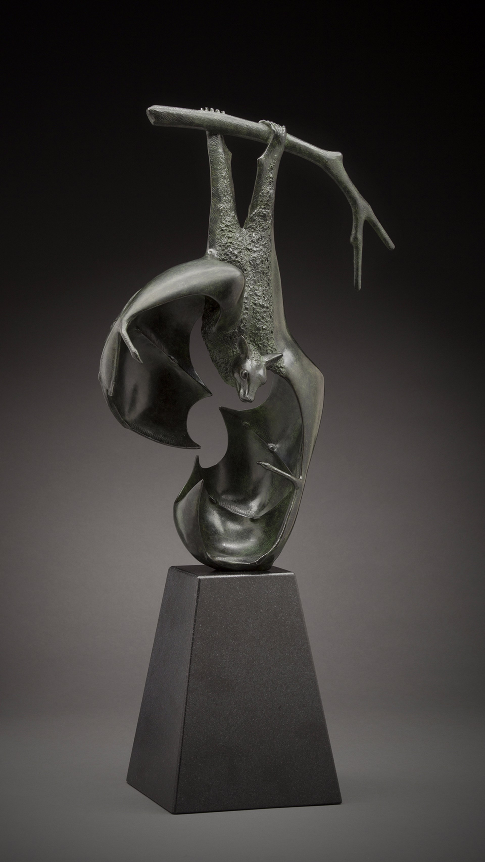 A sculptural composition featuring a textured, inverted figure suspended over a smooth, abstract form.