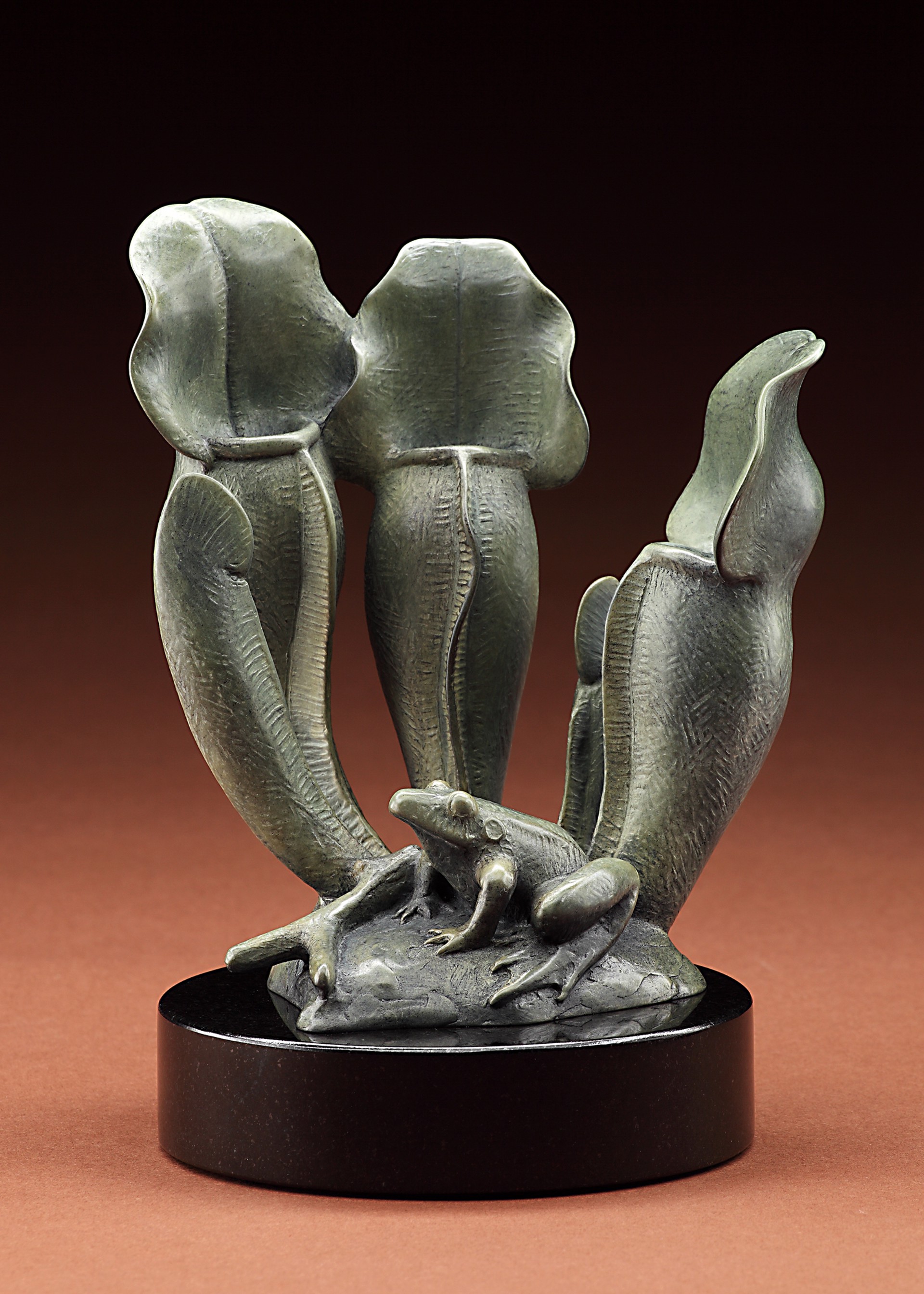 A sculptural piece featuring three pitcher plants surrounding a small frog.