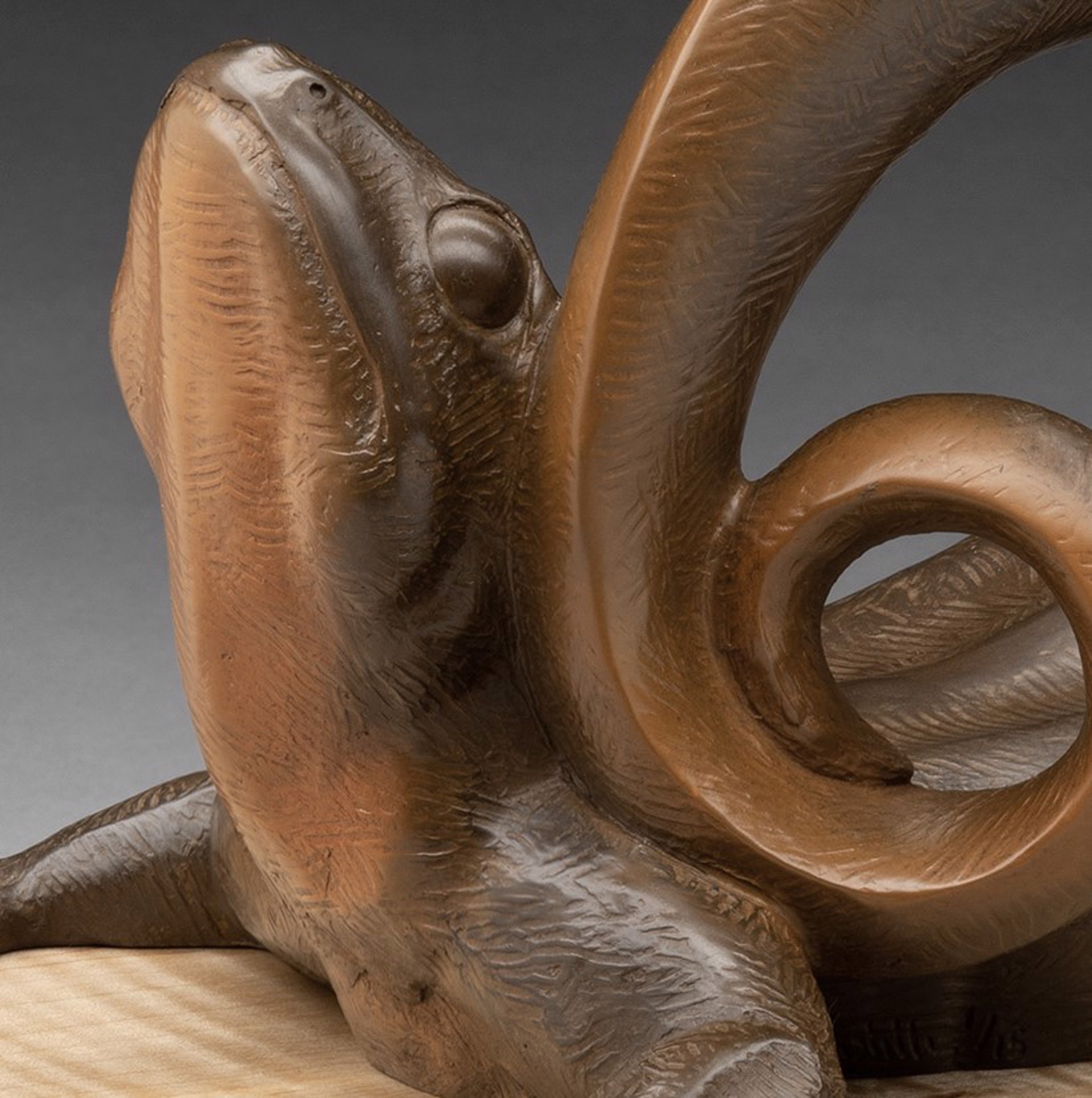 A bronze sculpture of a lizard on a wooden base.