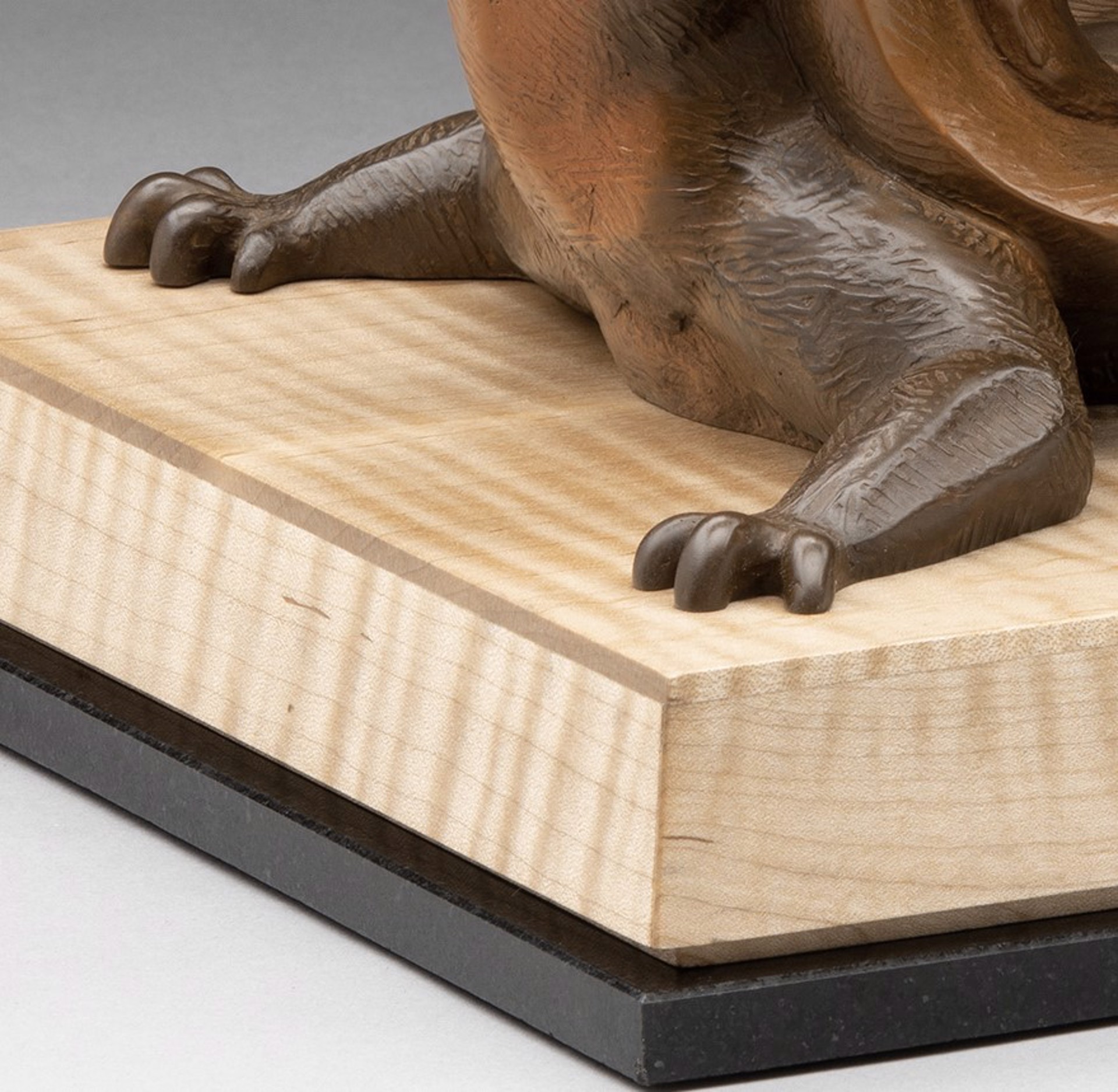 A bronze sculpture of a lizard on a wooden base.