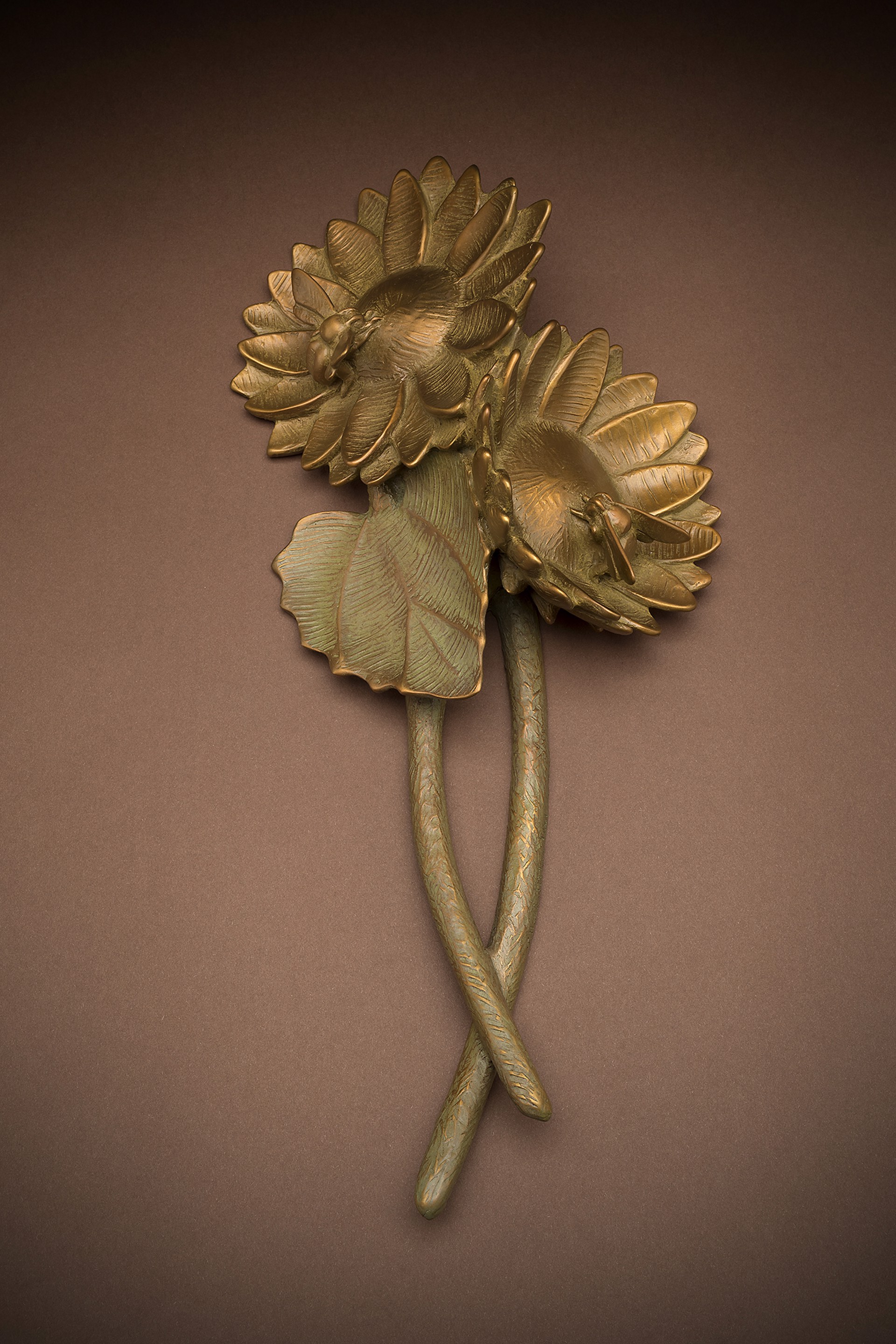 A pair of brass flowers on a brown background.